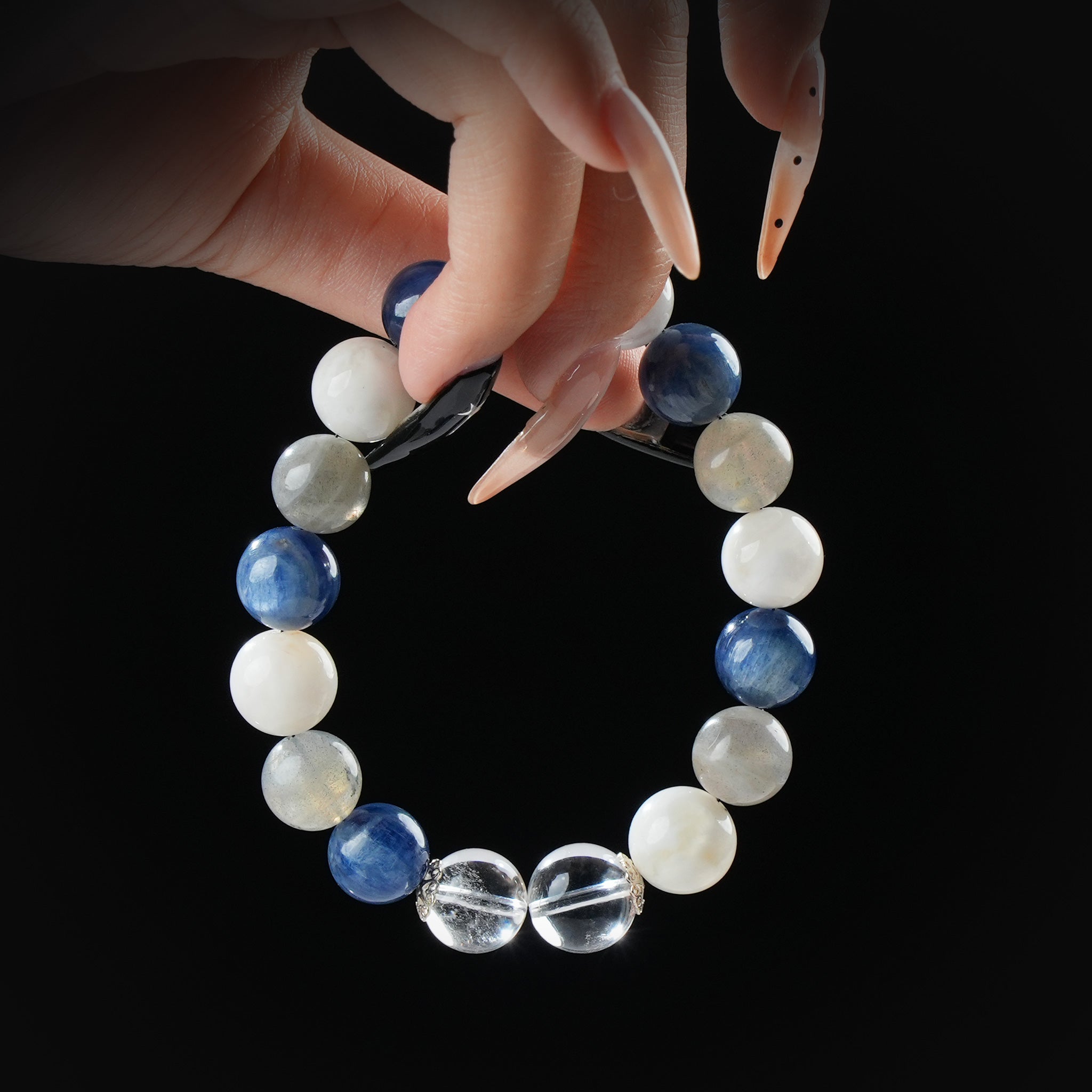 Kyanite, moonstone, labradorite, and clear quartz beaded bracelet held by hand on black background for calm, clarity, and spiritual alignment.