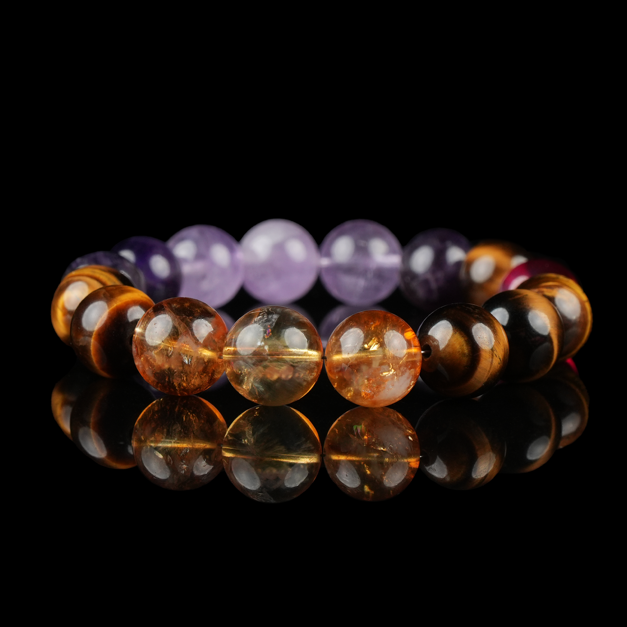 A detailed shot of a gemstone bracelet composed of radiant citrine, deep amethyst, golden tiger eye, and glossy red garnet beads, reflecting elegantly on a glossy black background