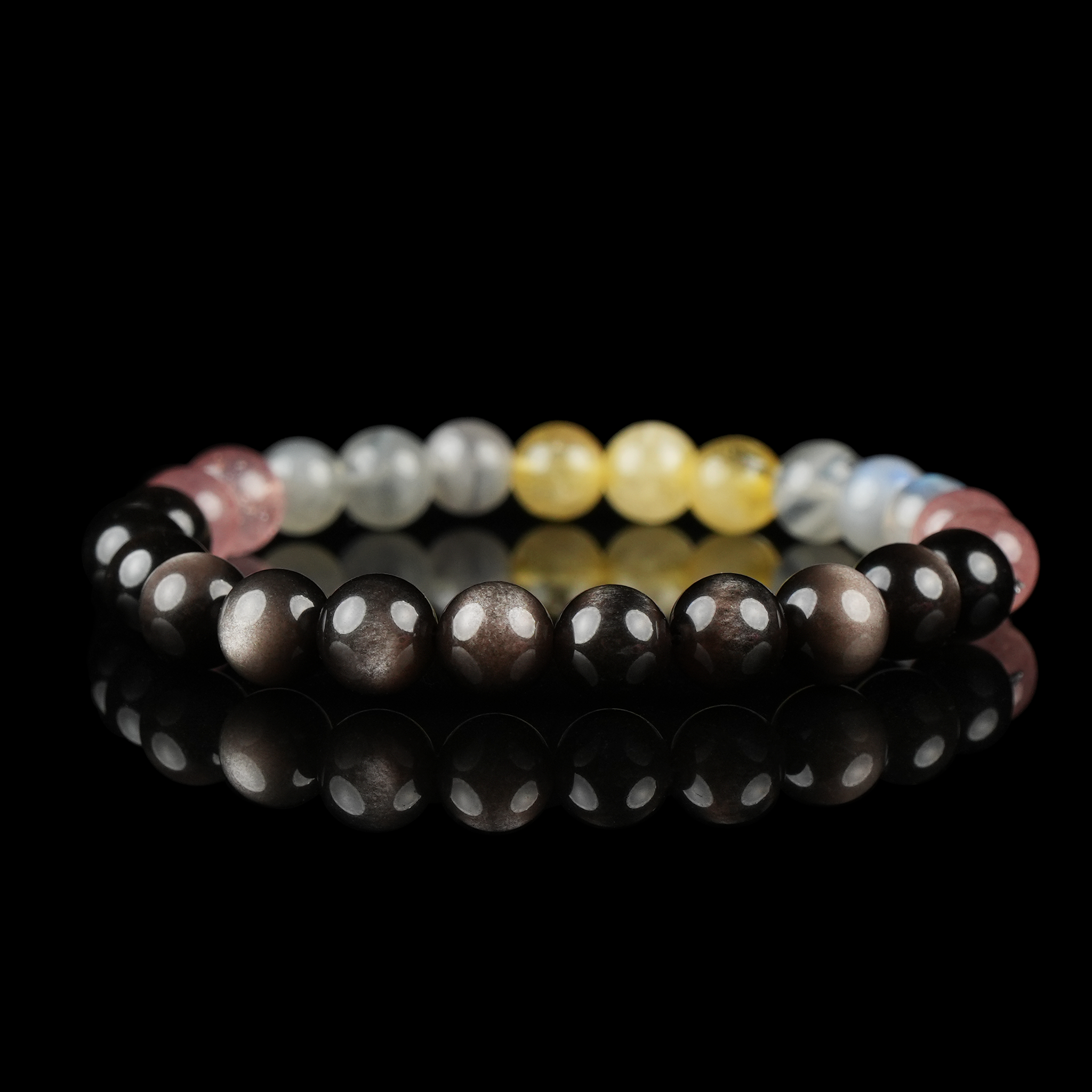 Bracelet featuring natural silver sheen obsidian, grey moonstone, strawberry quartz, and citrine beads on a reflective black surface.