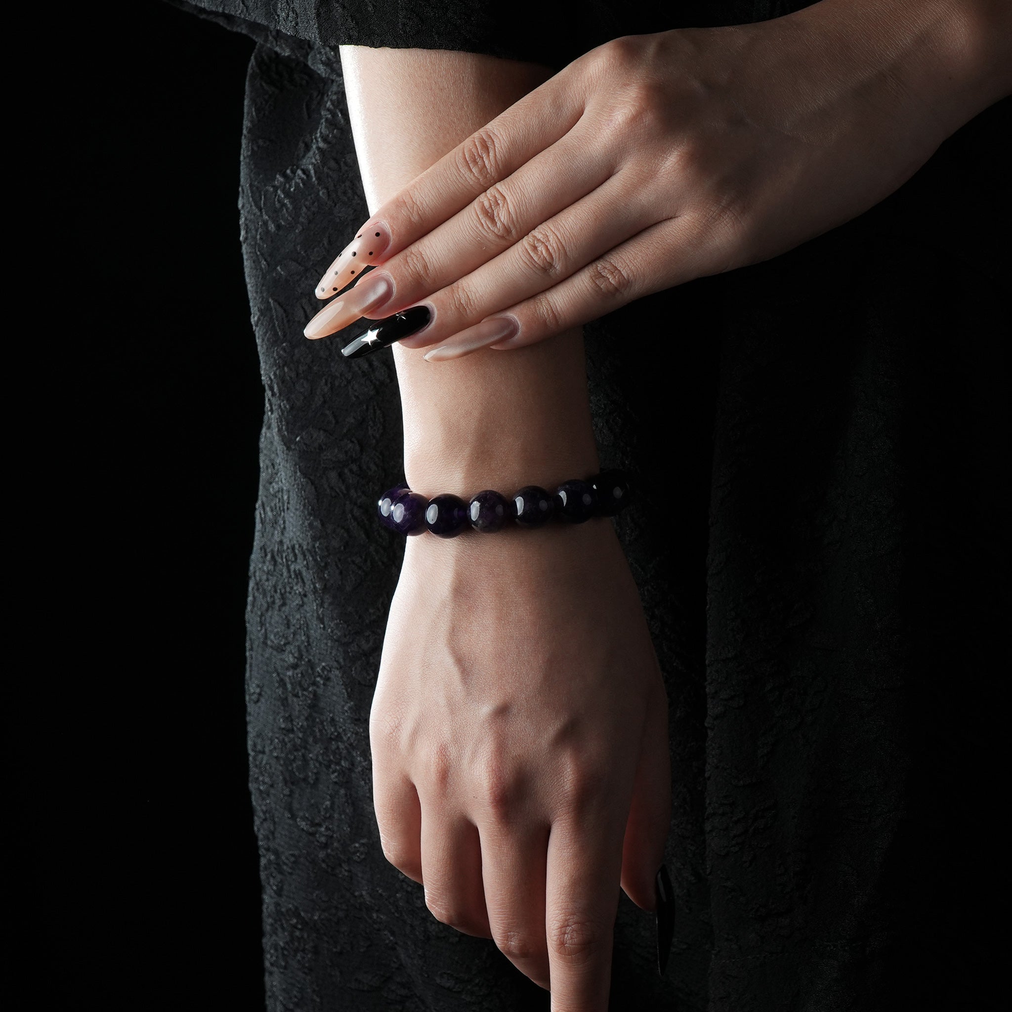 A model wearing the bracelet on the wrist, dressed in black, emphasizing the elegance and celestial glow of the Amethyst and Blue Goldstone beads against the skin.