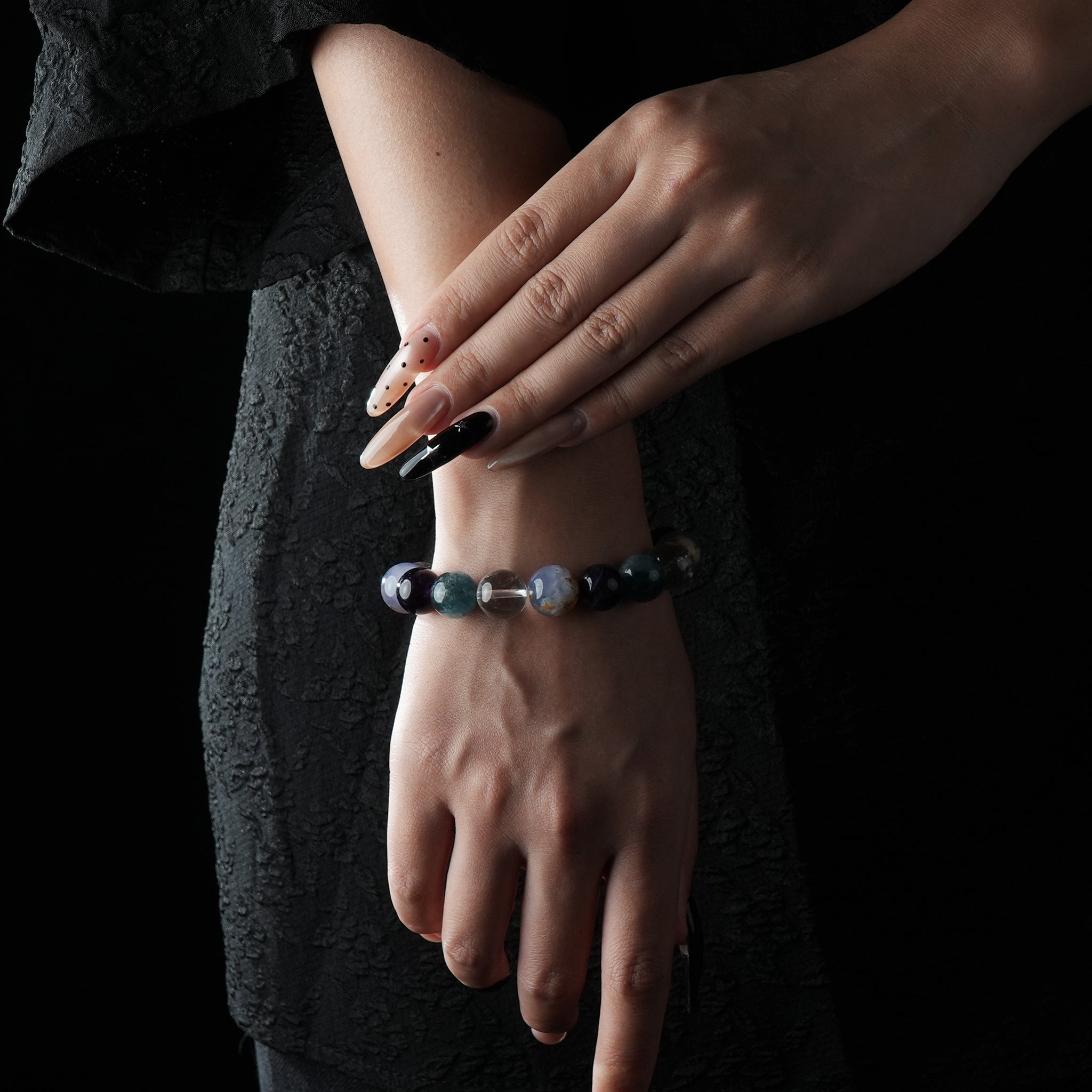 A beaded bracelet with deep purple Amethyst, soft blue Aquamarine, and clear White Crystal stones, elegantly worn on the wrist.