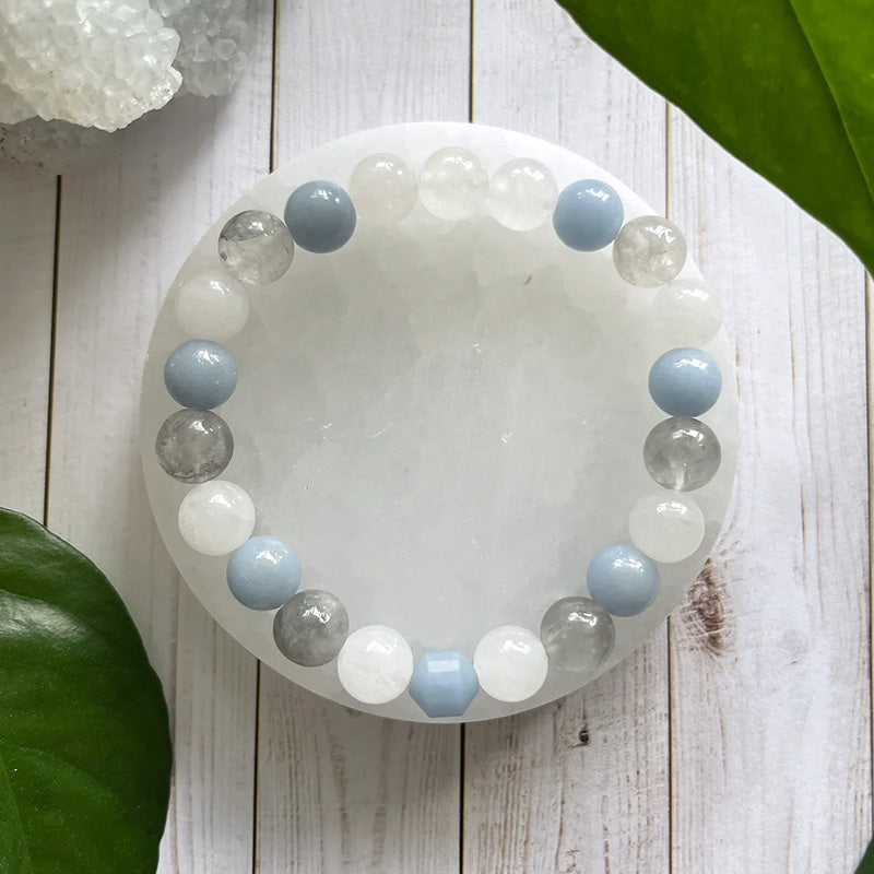 Bracelet placed on a white crystal dish with natural background, showcasing translucent and pastel stones that evoke calmness and spiritual clarity.