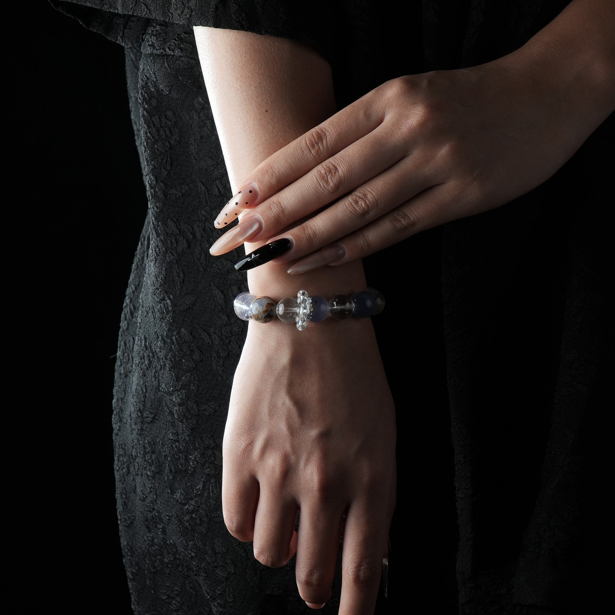 A bracelet made of soft blue Aquamarine and clear White Crystal beads, worn on the wrist with a black lace dress.