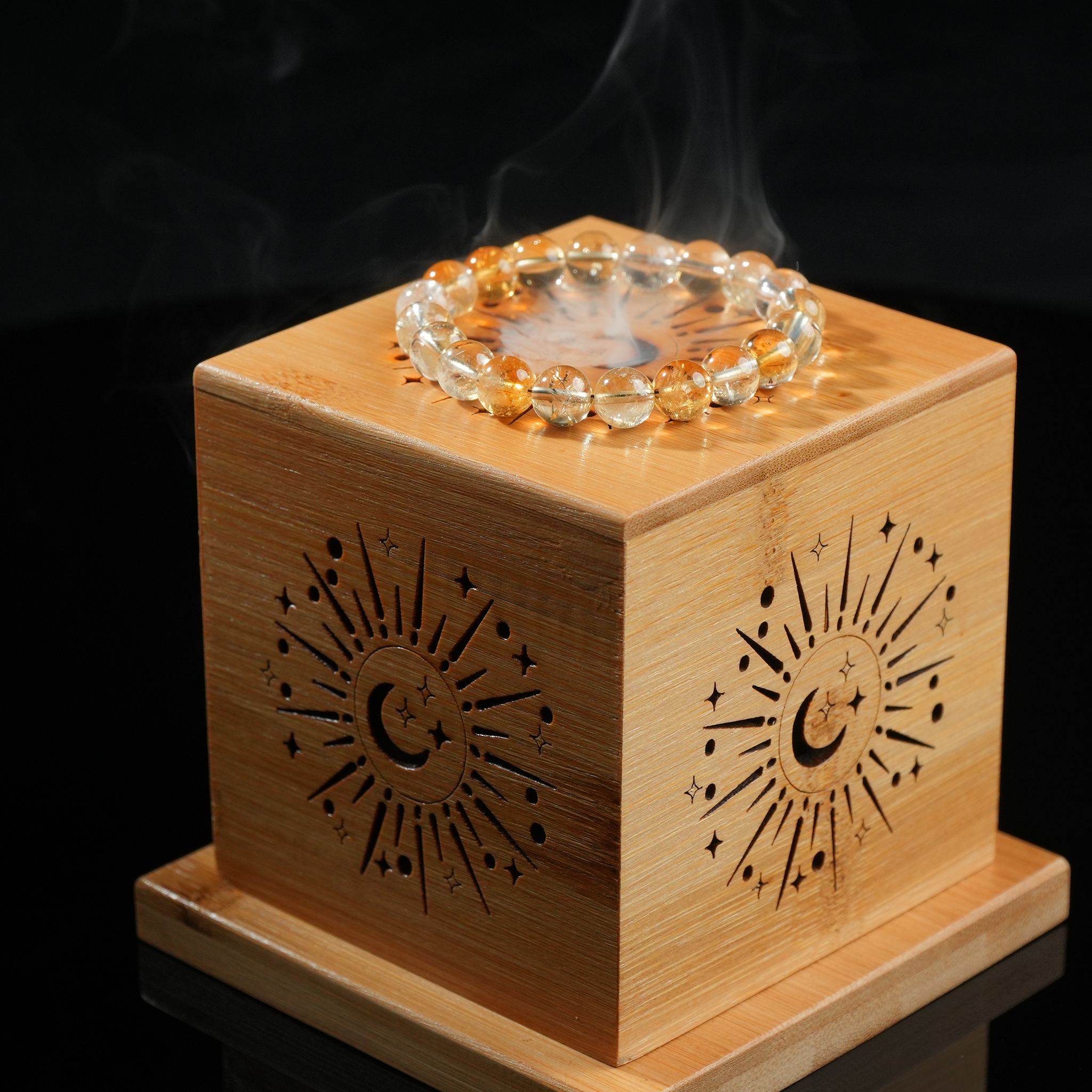 Bracelet sits on bamboo cube smudge box, light smoke visible around it.