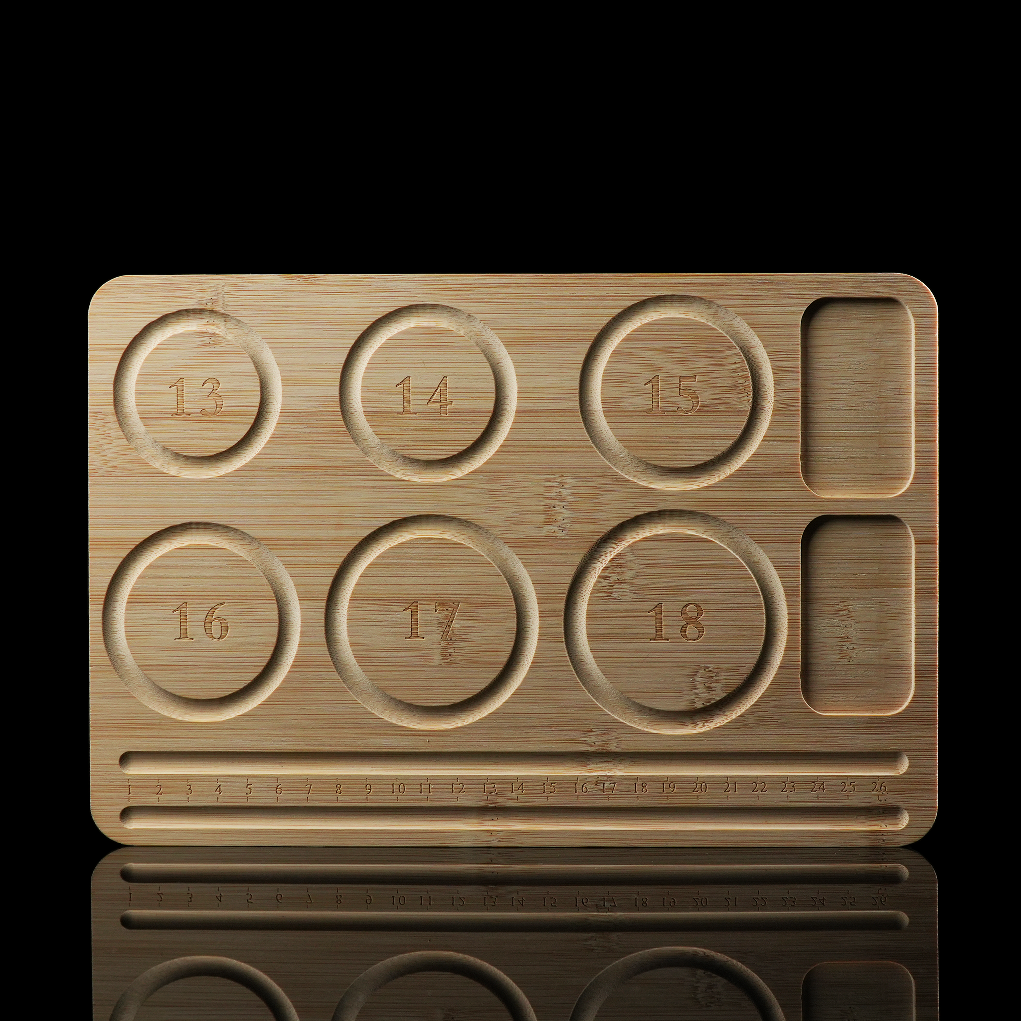 A top-down view of a rectangular bamboo jewelry design tray featuring six engraved circular grooves labeled with bead sizes from 13 to 18 mm. It also includes ruler markings and two rectangular compartments for tools or components.