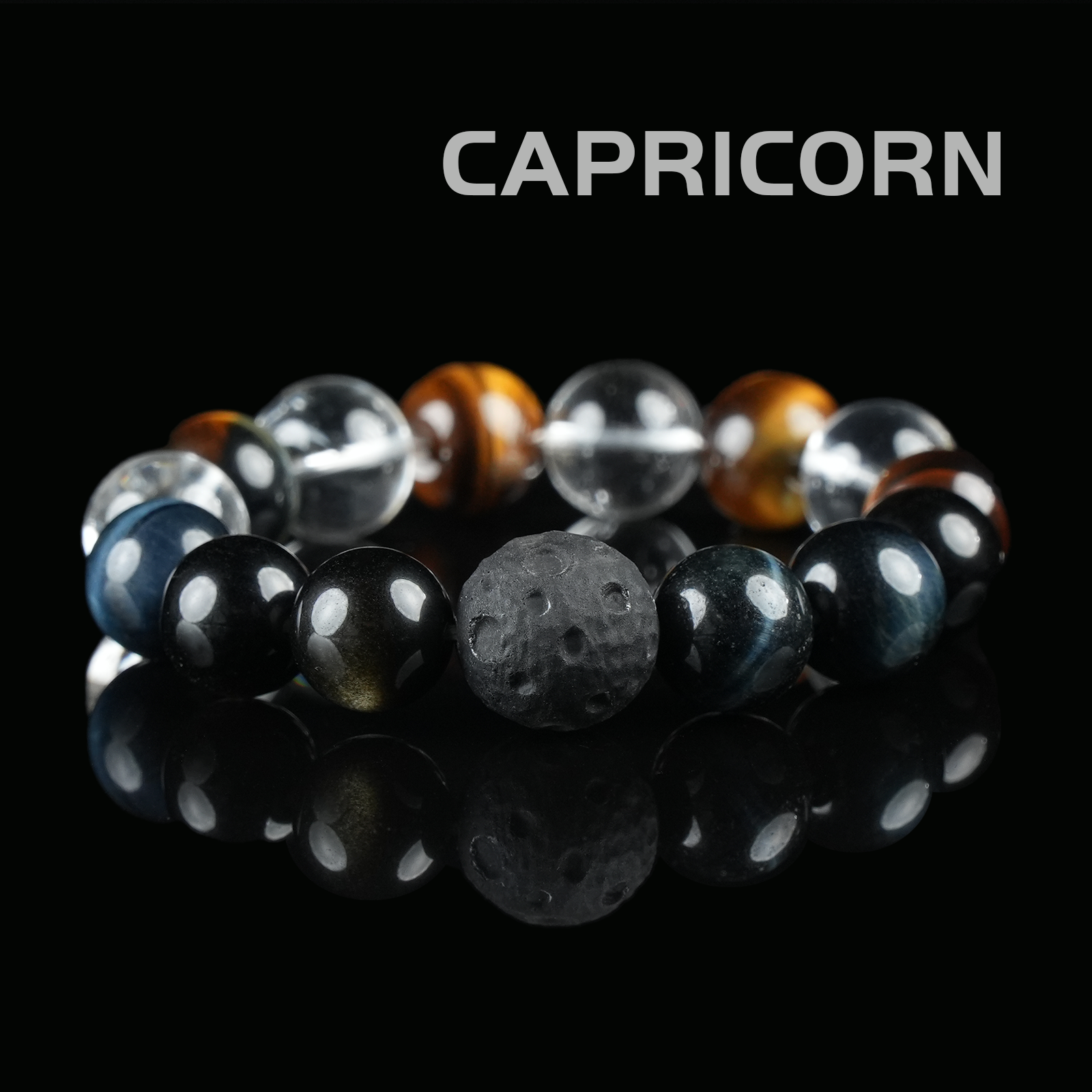Flat lay of Capricorn zodiac crystal bracelet with tiger eye, obsidian, lava stone, and clear quartz beads on black reflective background.