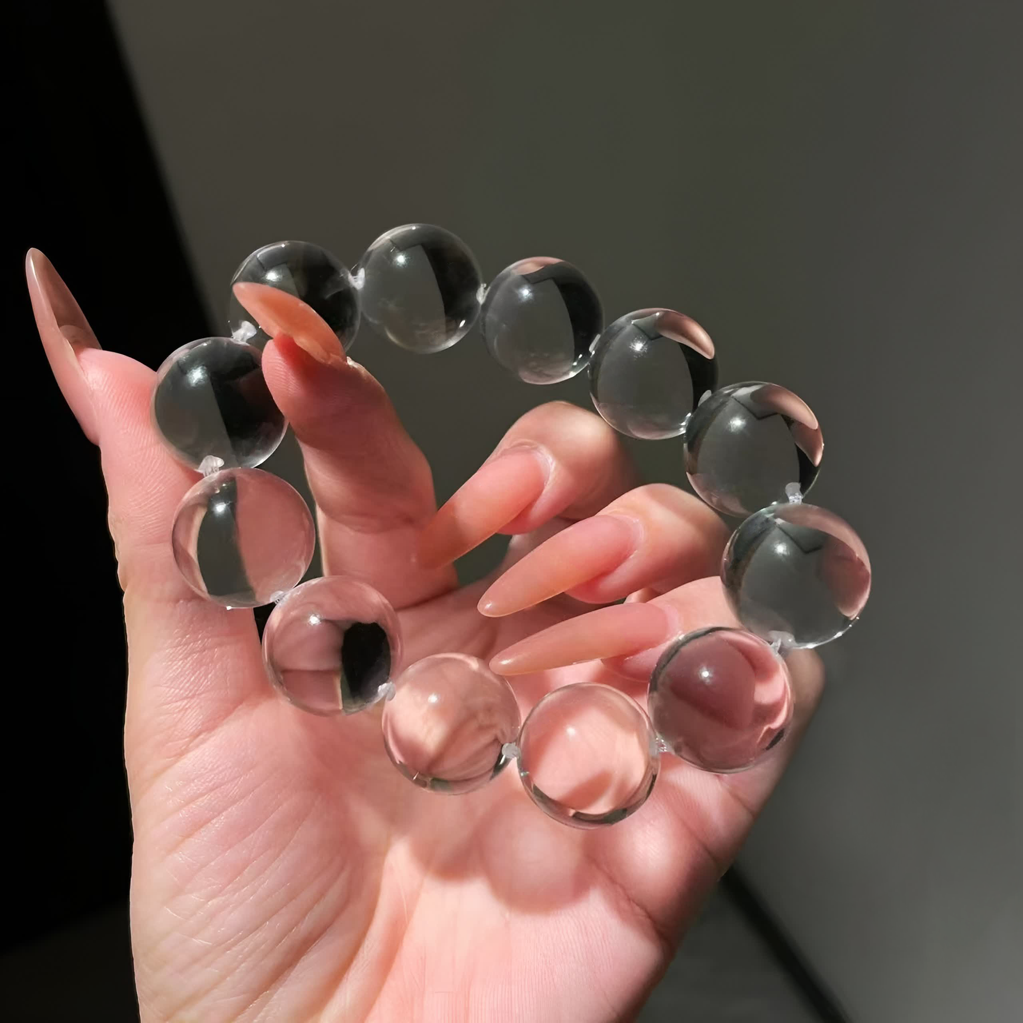 Close-up view of a clear quartz crystal bracelet, light reflecting off each transparent bead.