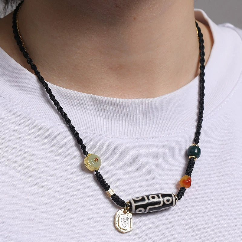 A detailed view of a Tibetan 9-Eye Dzi Agate necklace showcasing the black and white design of the Dzi bead, complemented by gold and jade accents, highlighting the fine craftsmanship.