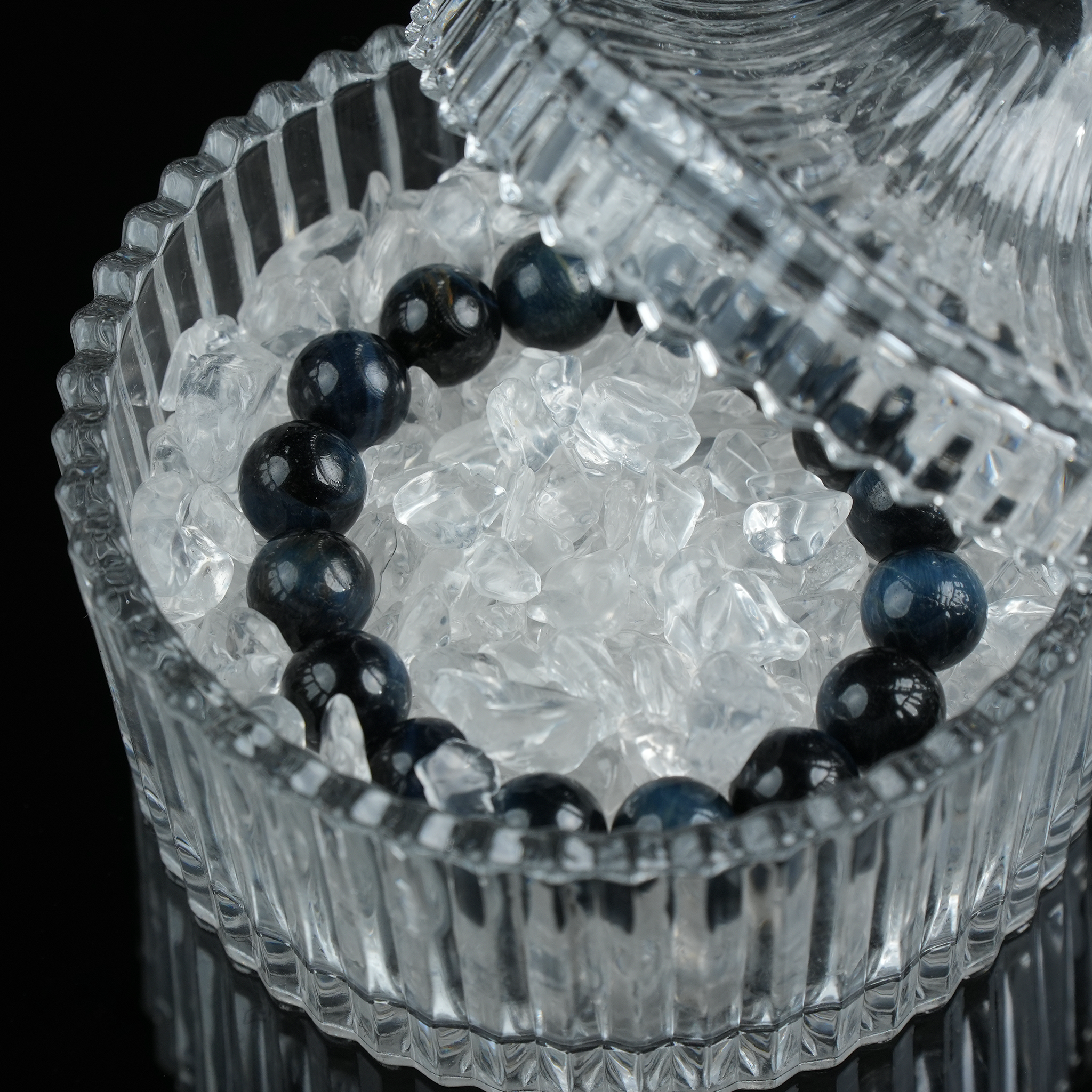 A gemstone bracelet placed in a glass bowl filled with cleansing crystals, symbolizing energy recharging.