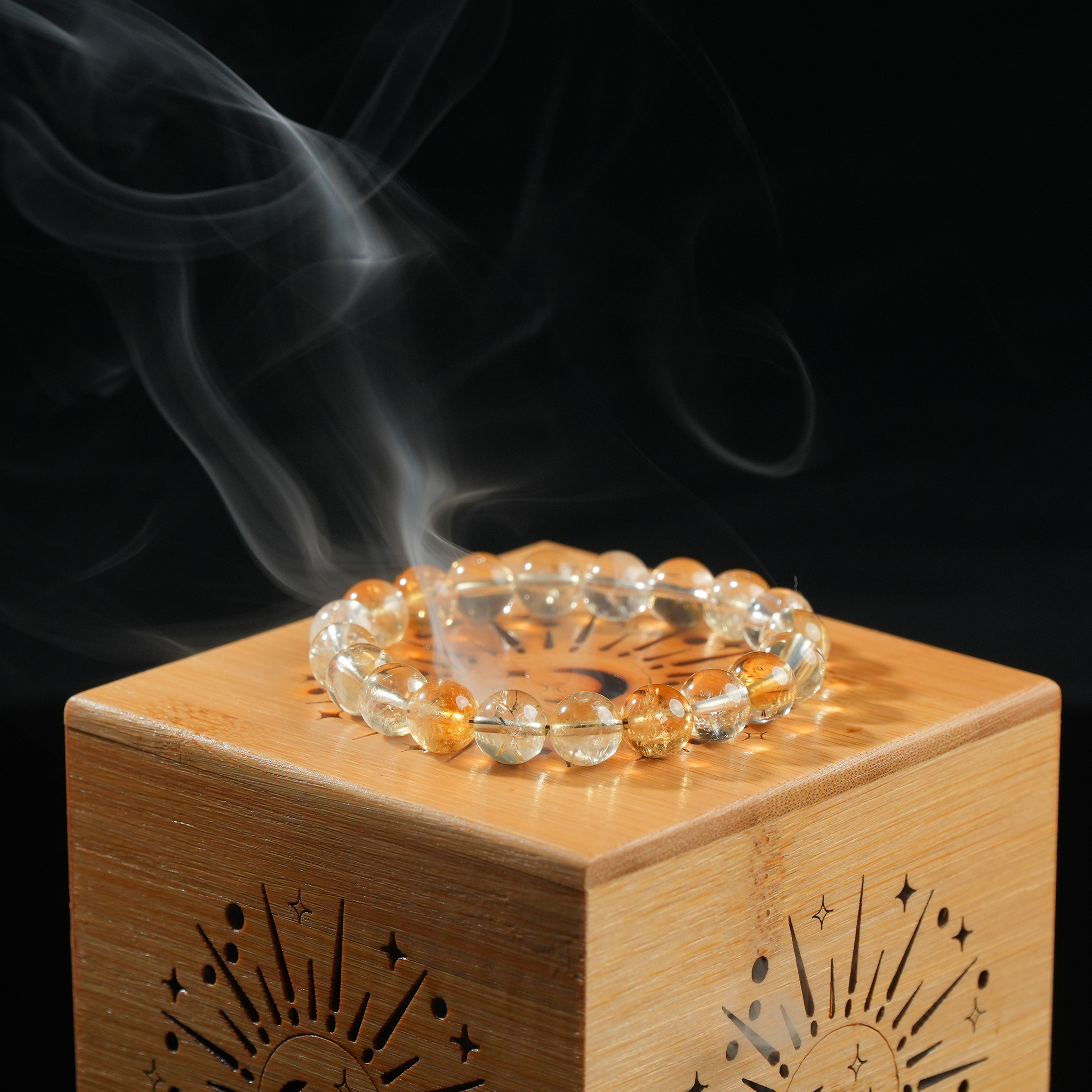 Close-up of gemstone bracelet on bamboo lid, smoke curling in soft light above it.