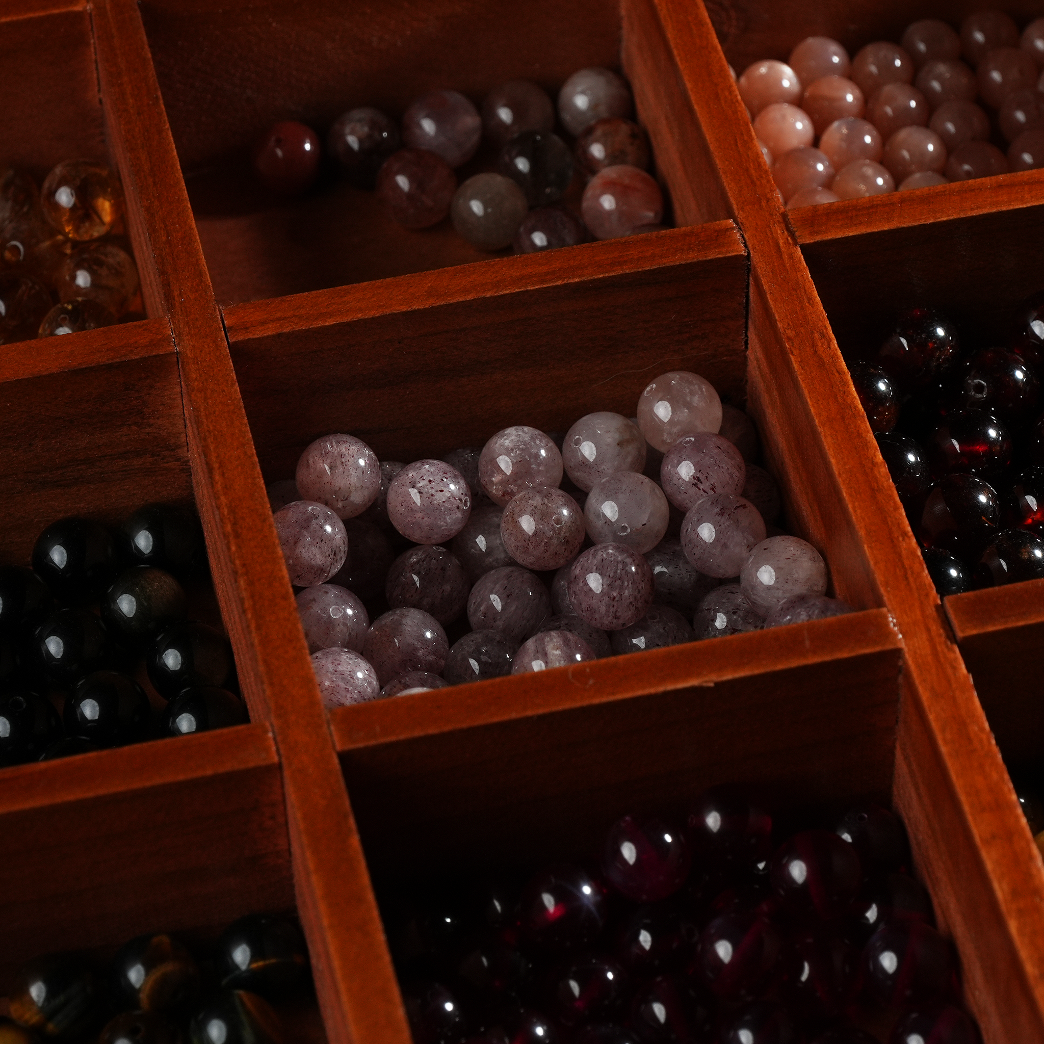 The wooden organizer is partially filled with assorted crystal beads of various colors and sizes, demonstrating how the compartments can be used for storing jewelry components or small collectibles.