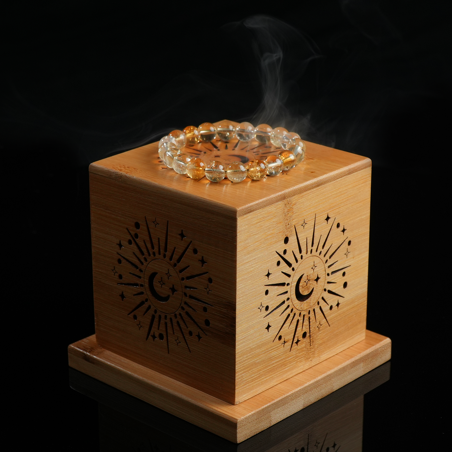 A yellow crystal bracelet resting atop a celestial-themed wooden sage burner.