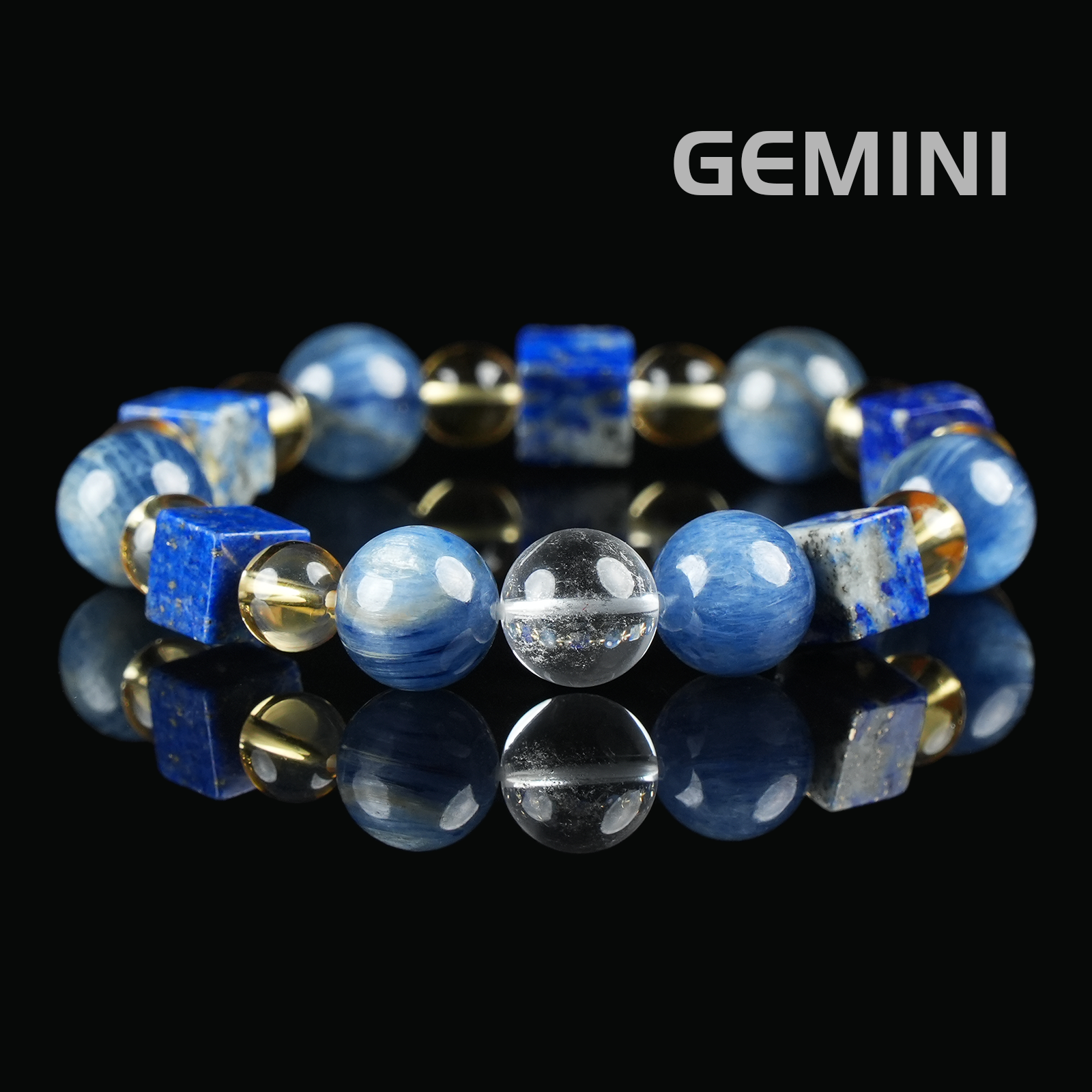 Flat lay of Gemini zodiac bracelet with deep blue lapis lazuli cubes, round kyanite beads, clear quartz, and golden citrine spacers on black reflective surface.