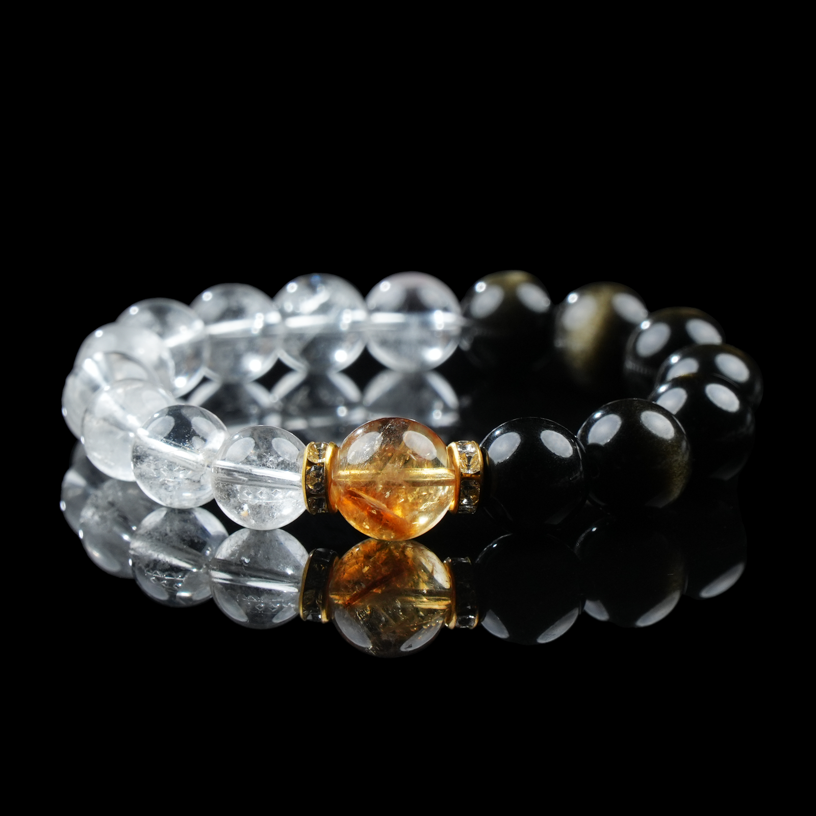 A gemstone bracelet featuring alternating gold obsidian and clear quartz beads, centered with a radiant citrine bead accented by gold-toned spacers.