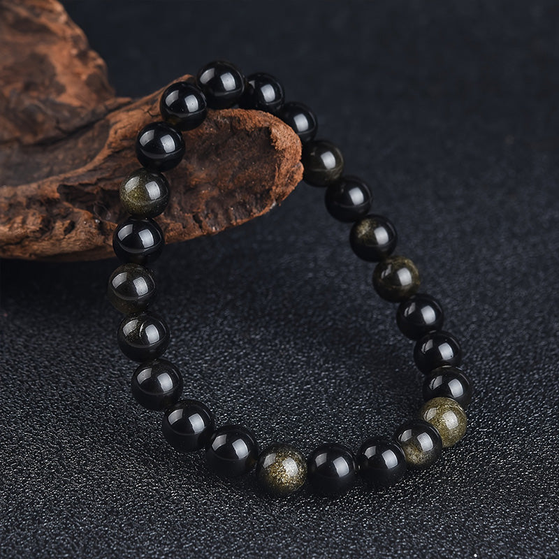 Tight shot of obsidian bracelet highlighting bead detail and subtle golden sheen, emphasizing focus, grounding, and quiet resilience.