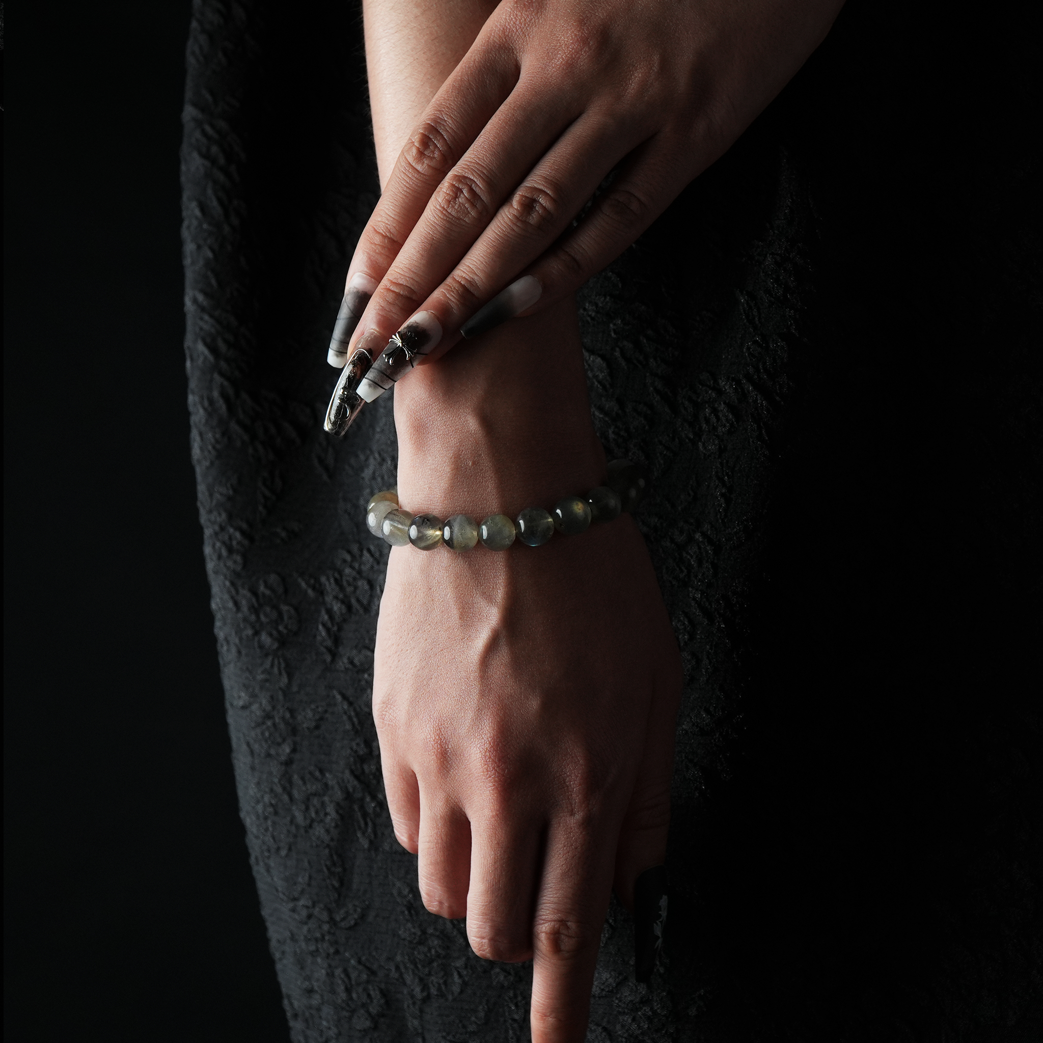 A smooth, gray-toned Moonstone beaded bracelet displayed on a wrist.