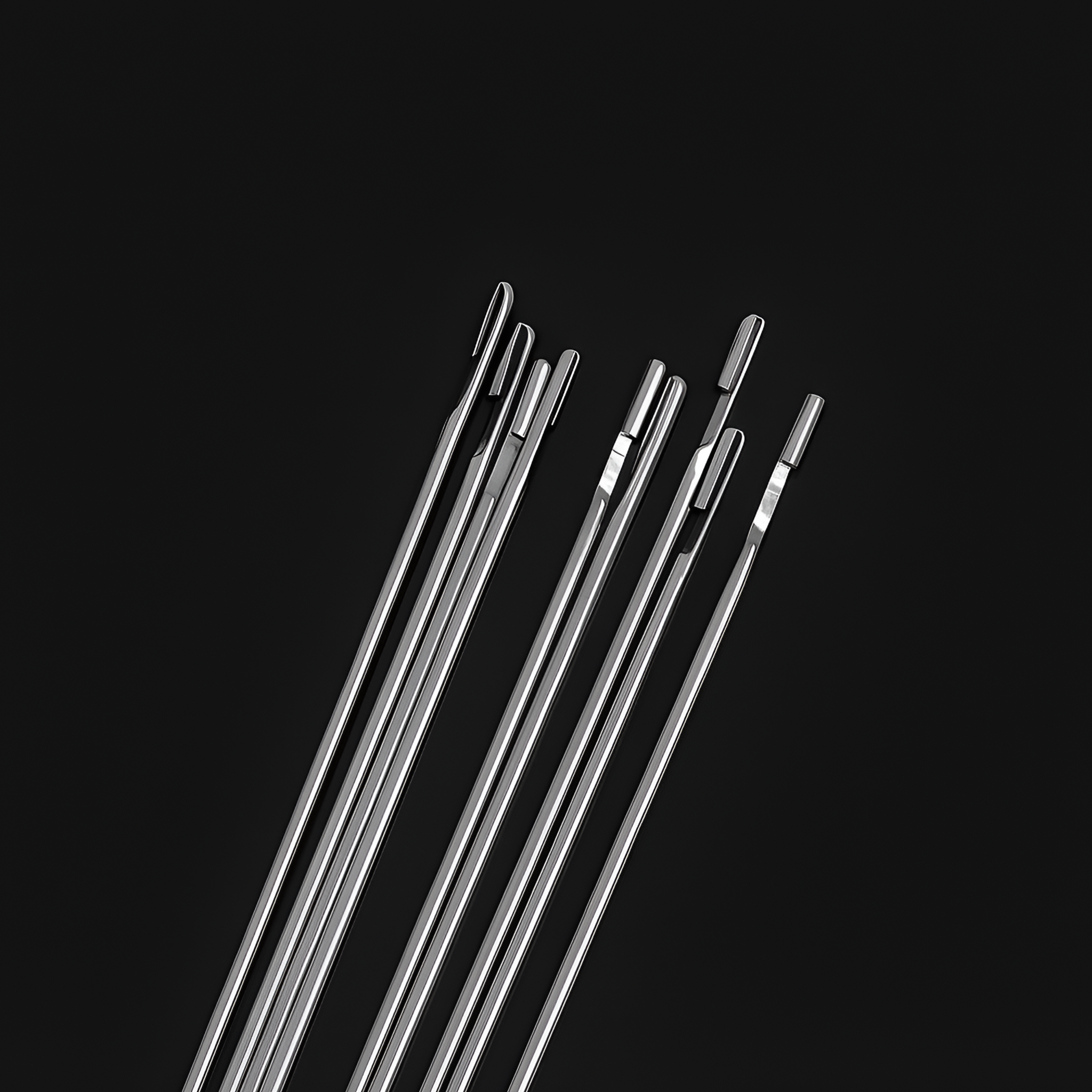 A zoomed-in shot of the needle heads, focusing on the different sizes and shapes of the eyes. The craftsmanship and polished finish of the stainless steel material are clearly visible.