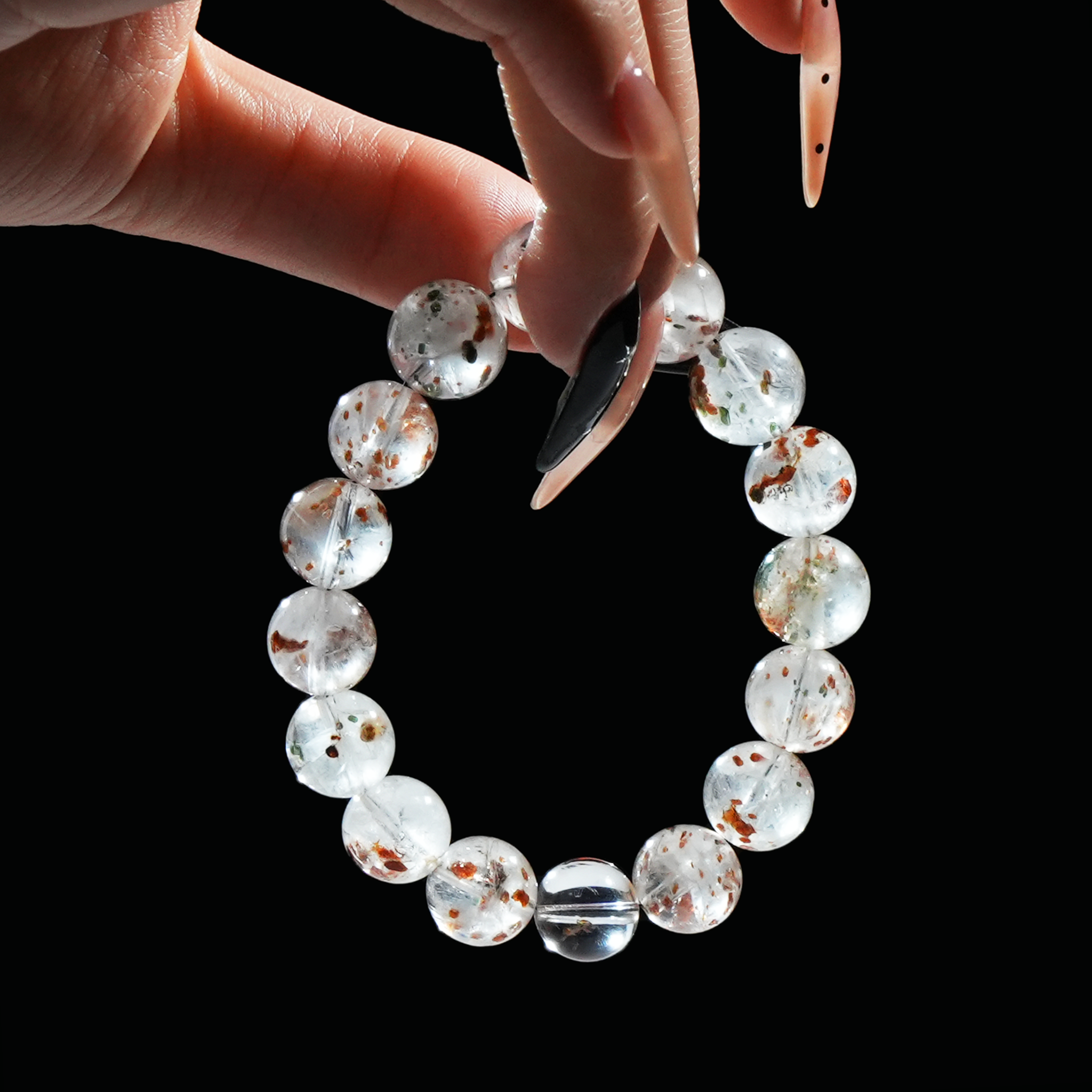 Close-up of hand holding white phantom quartz bracelet with dreamy phantom inclusions – known for clarity, growth, and trending on TikTok.