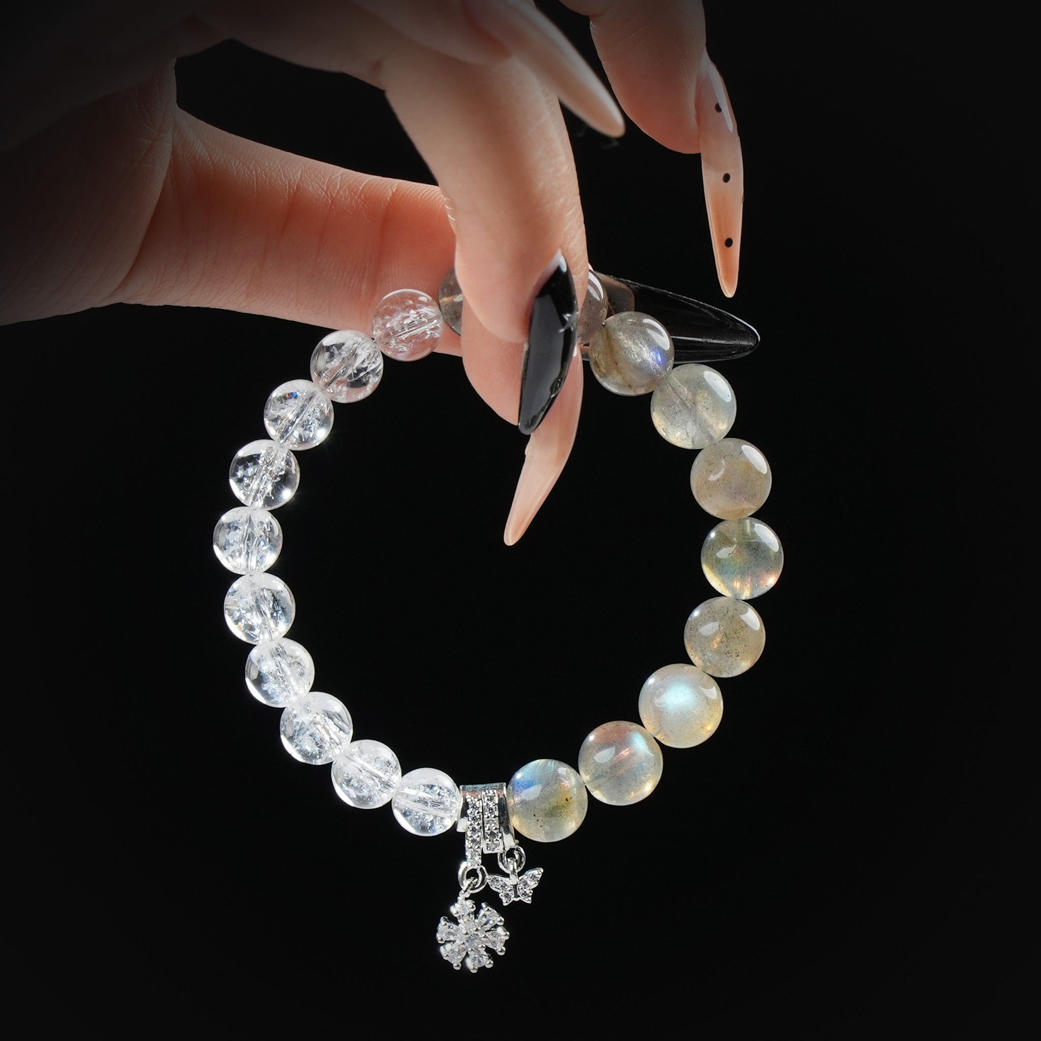 Hand holding grey moonstone and Himalayan quartz bracelet with silver charms