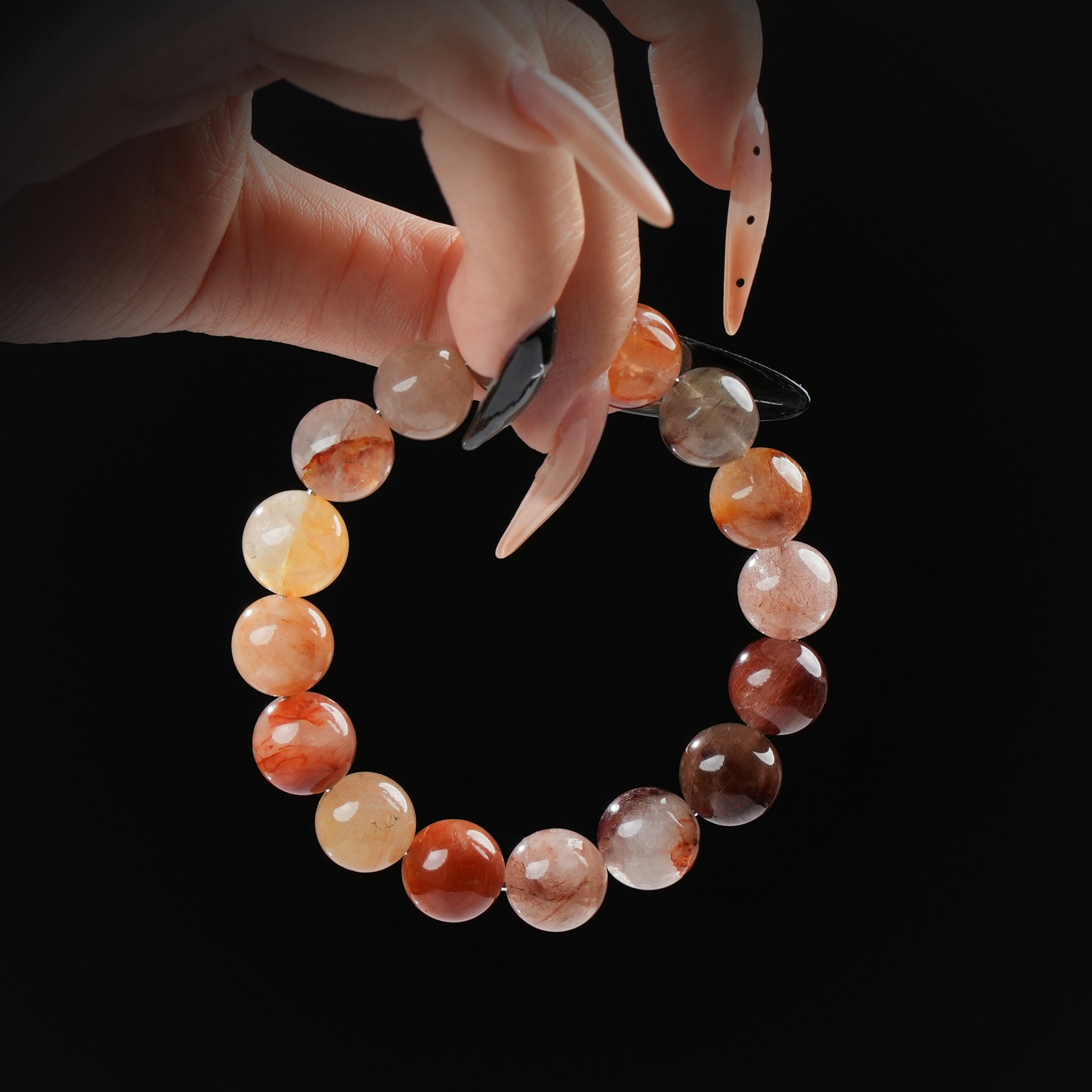 A hand gently holds a circular red hematoid quartz bracelet, revealing the stone's fiery internal textures and glossy finish under soft lighting.
