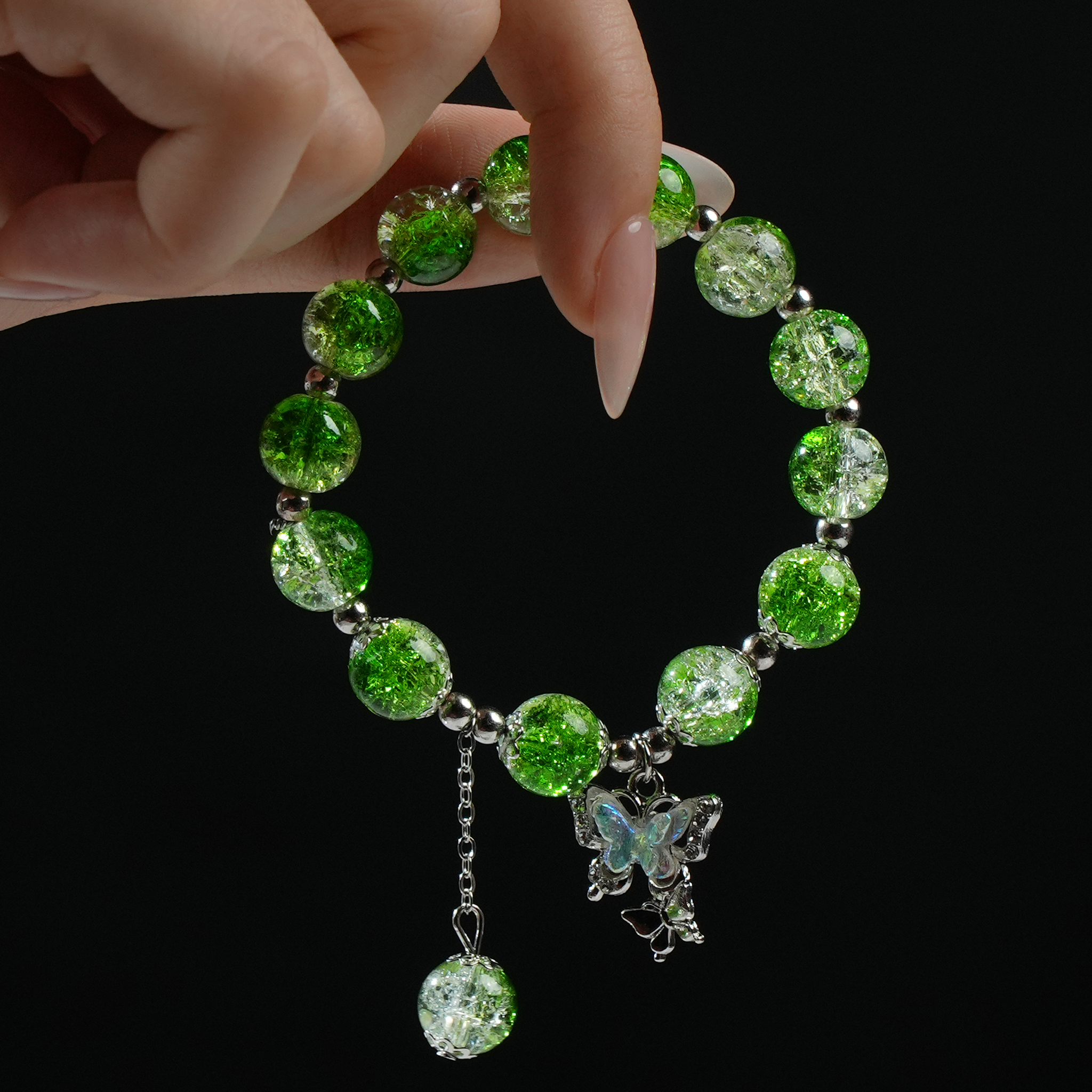 A green energy bead bracelet displayed in hand, decorated with a sparkling butterfly pendant—fresh, uplifting, and full of vitality.