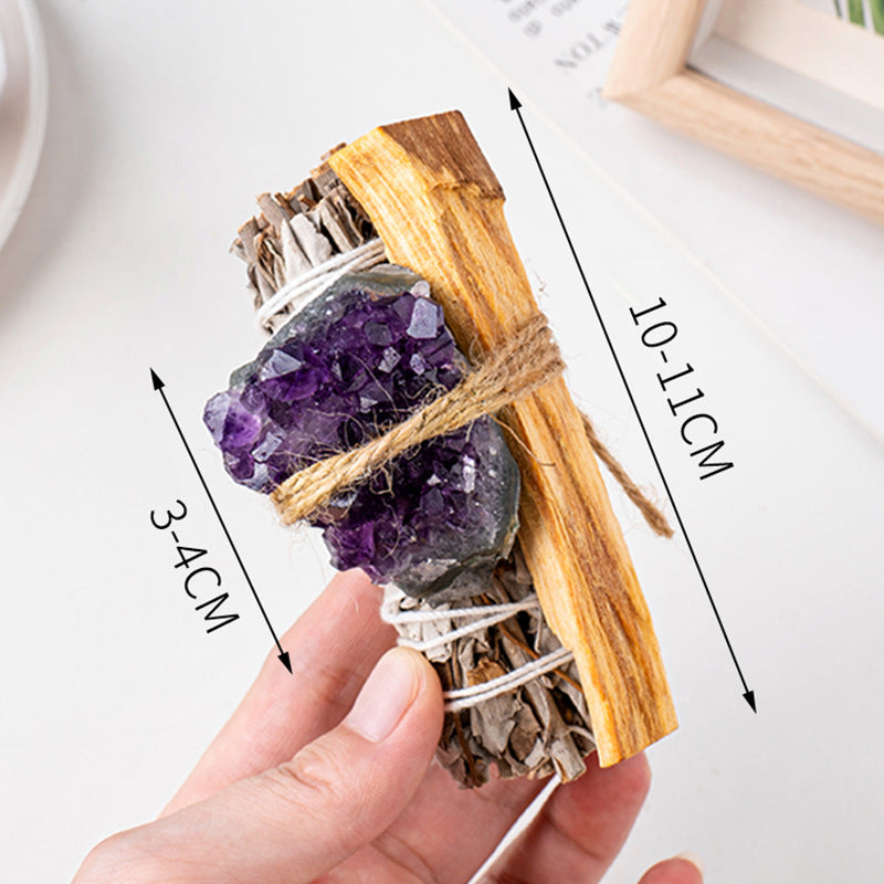 A hand holding a crystal-infused sage and palo santo bundle, showing size dimensions on a white background.