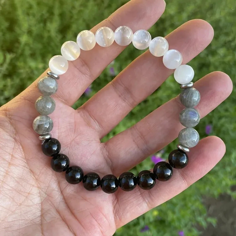 Bracelet displayed on a hand with natural lighting, combining shimmering cat’s eye and black obsidian beads to support intuition and ward off negativity.