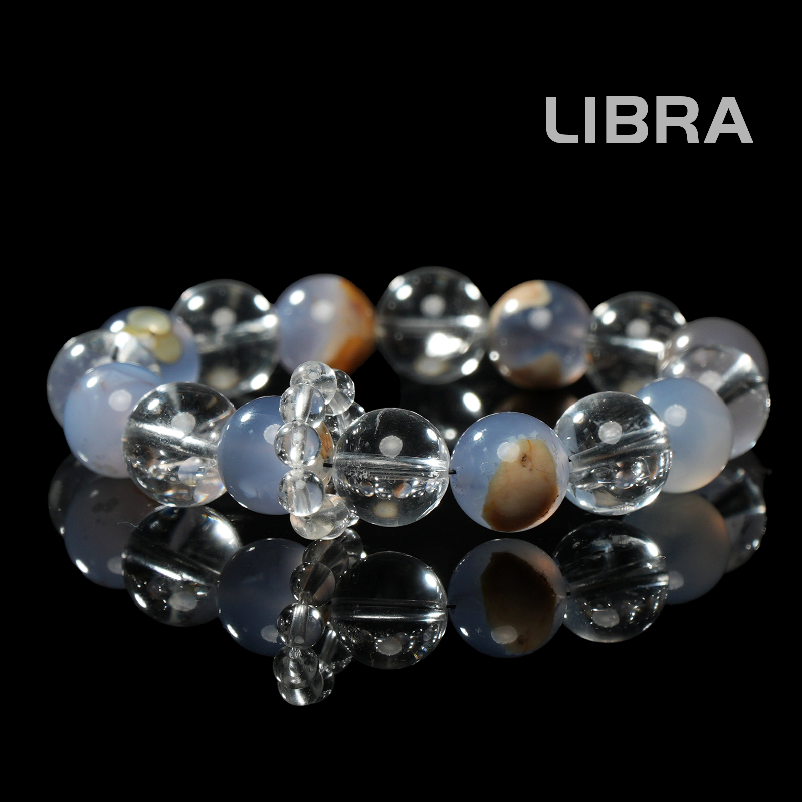 Flat lay of Libra zodiac bracelet made with soothing blue chalcedony and clear quartz beads, shown on black reflective background.