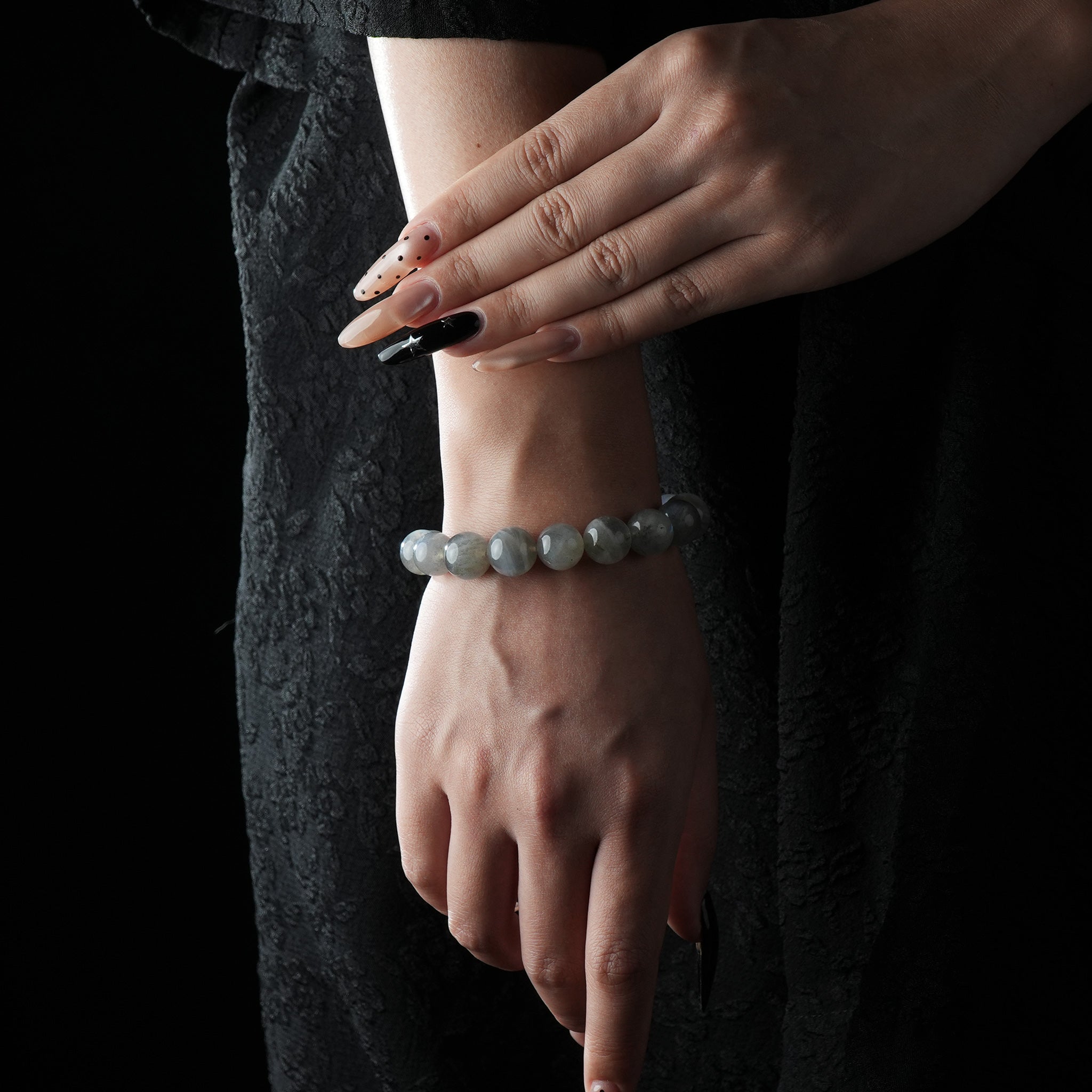 A close-up of a moonstone bracelet worn on the wrist, featuring smooth, round beads with a soft, shimmering glow.