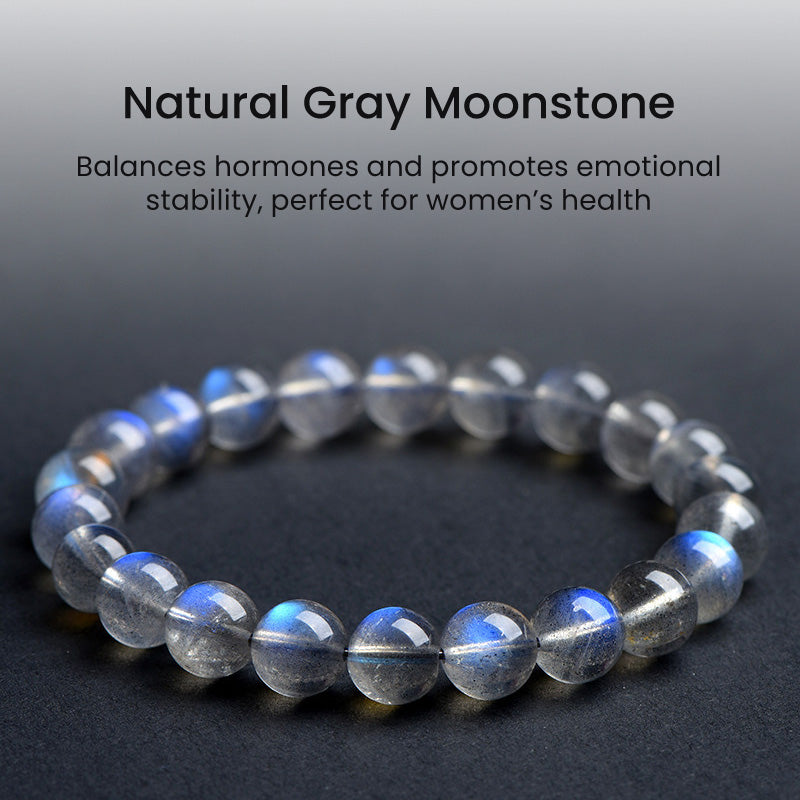 Gray moonstone bracelet with light text description, placed on a dark textured surface, highlighting the calming blue sheen typical of high-quality moonstone.
