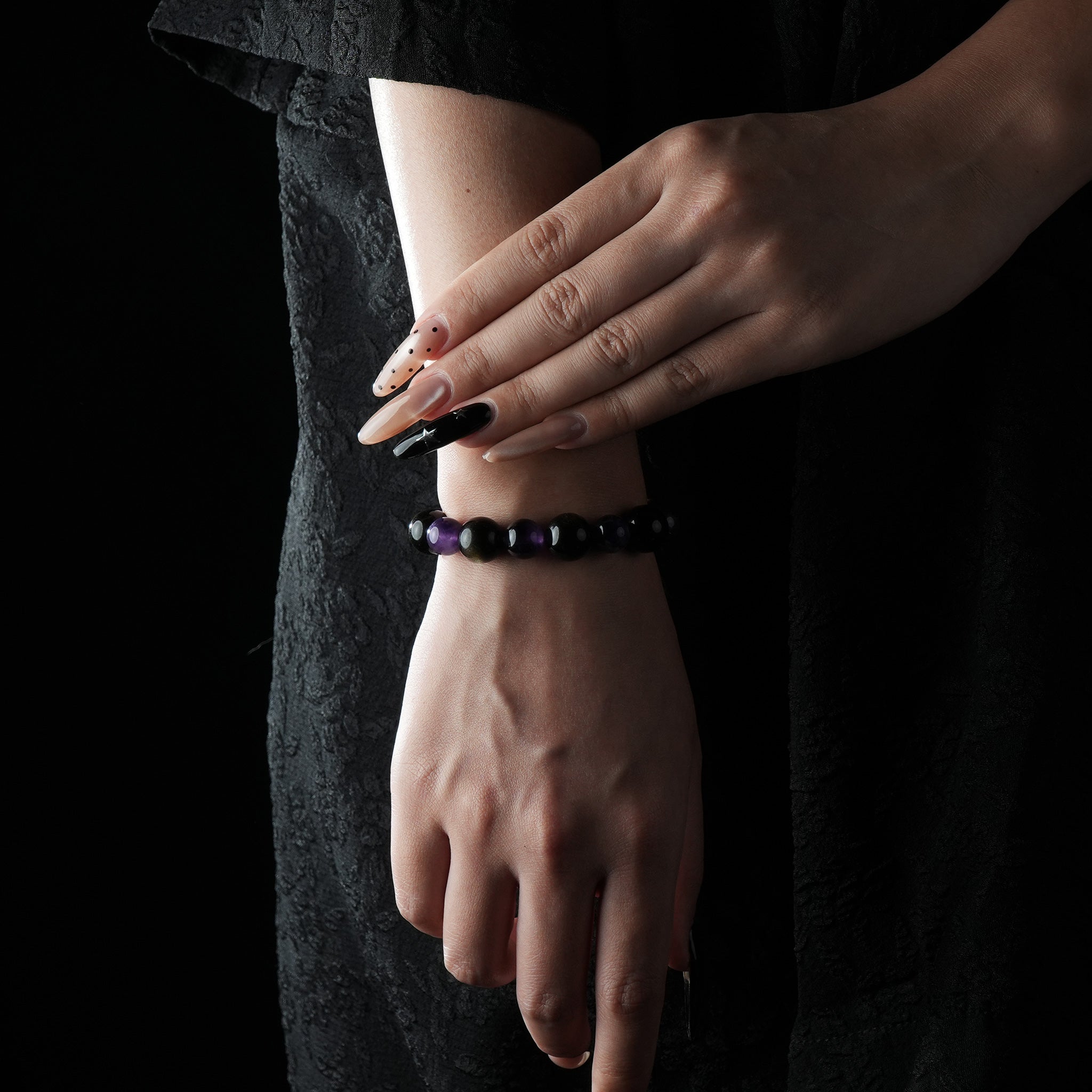 A simple black and purple bracelet made of obsidian and amethyst, worn on the wrist.