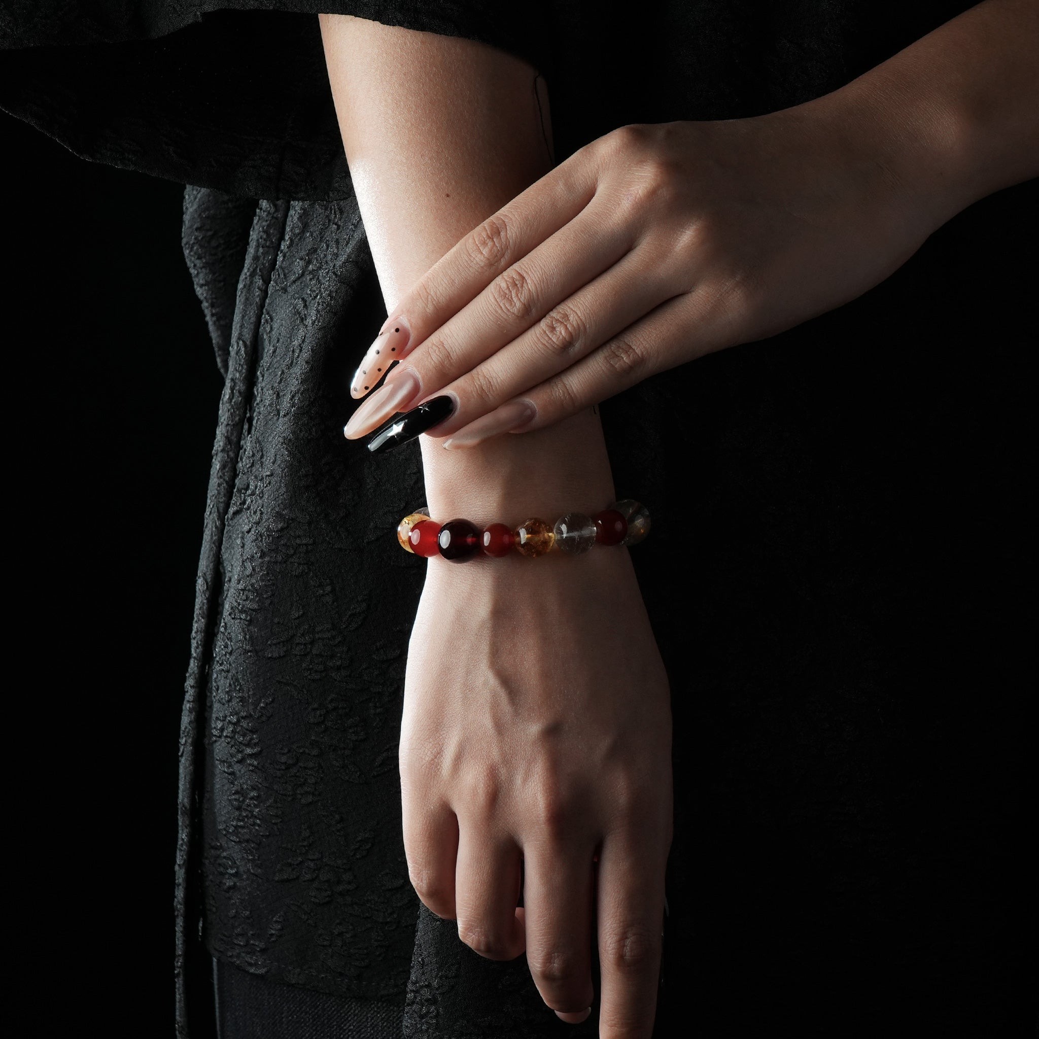 A vibrant beaded bracelet featuring red Agate, deep Garnet, and golden Citrine stones worn on the wrist.