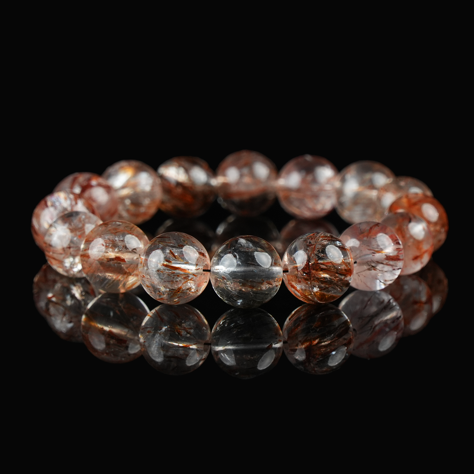 Flat lay of red rutilated quartz bracelet featuring high-transparency beads with vivid red rutile threads, on glossy black background.