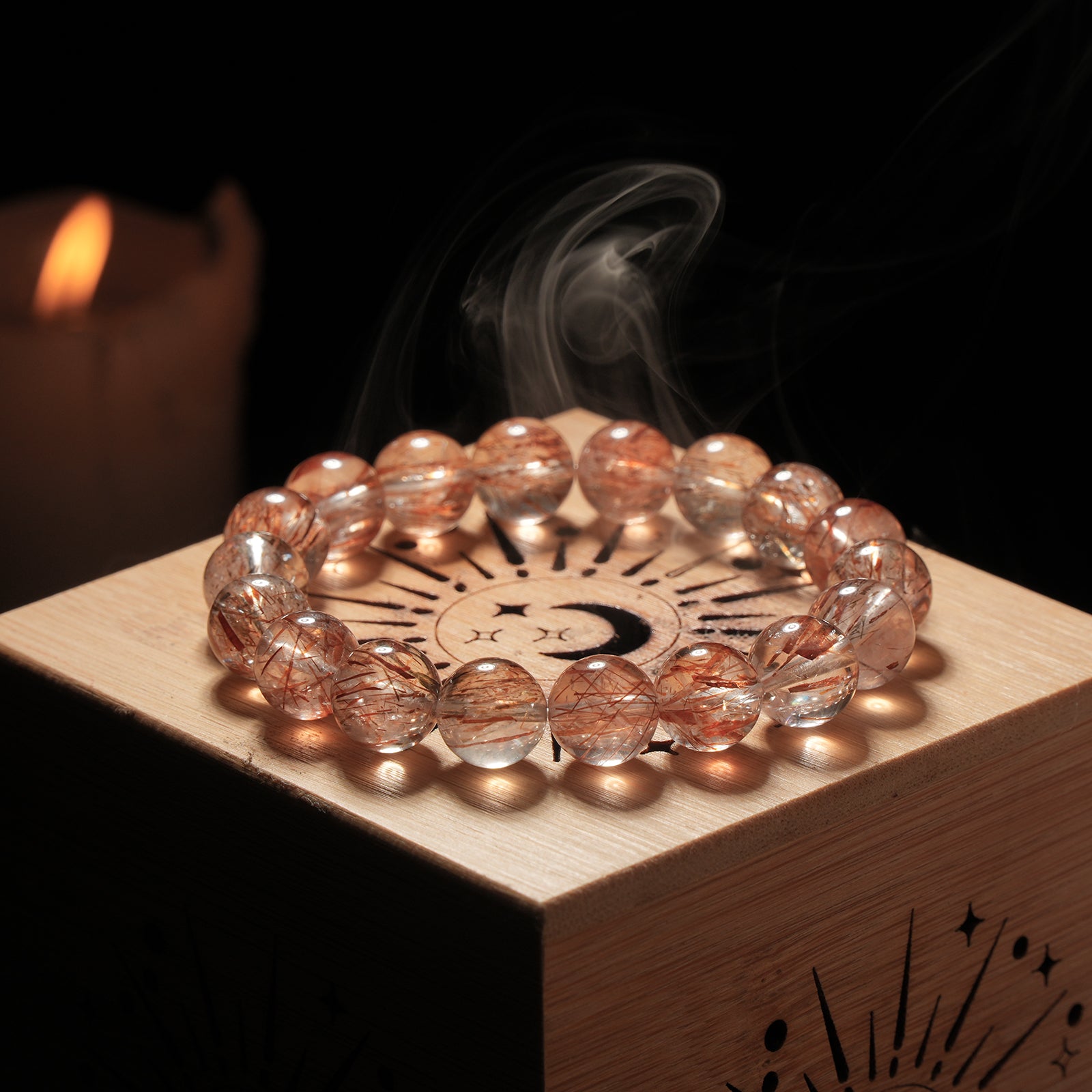 Red rutilated quartz bracelet placed on wooden altar with incense smoke rising – a setup for energy clearing and spiritual rituals.