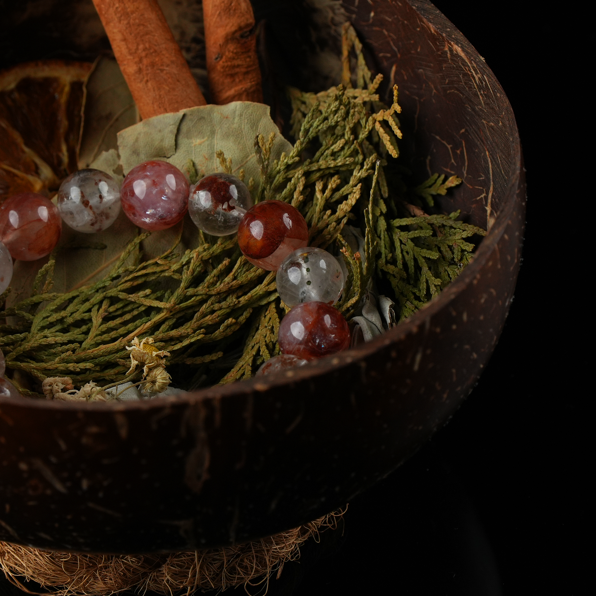 Detailed shot of bay leaves, herbs, and gemstones arranged naturally in a carved coconut shell bowl.