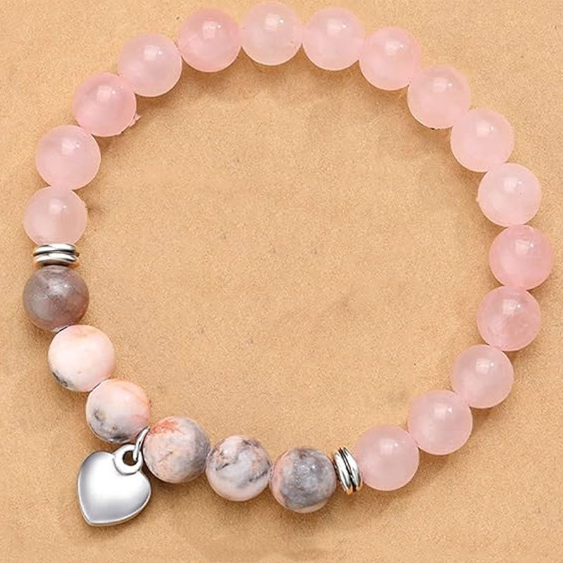 A bracelet with pink beads and natural stones arranged on a neutral brown background, showcasing its gentle and harmonious design.