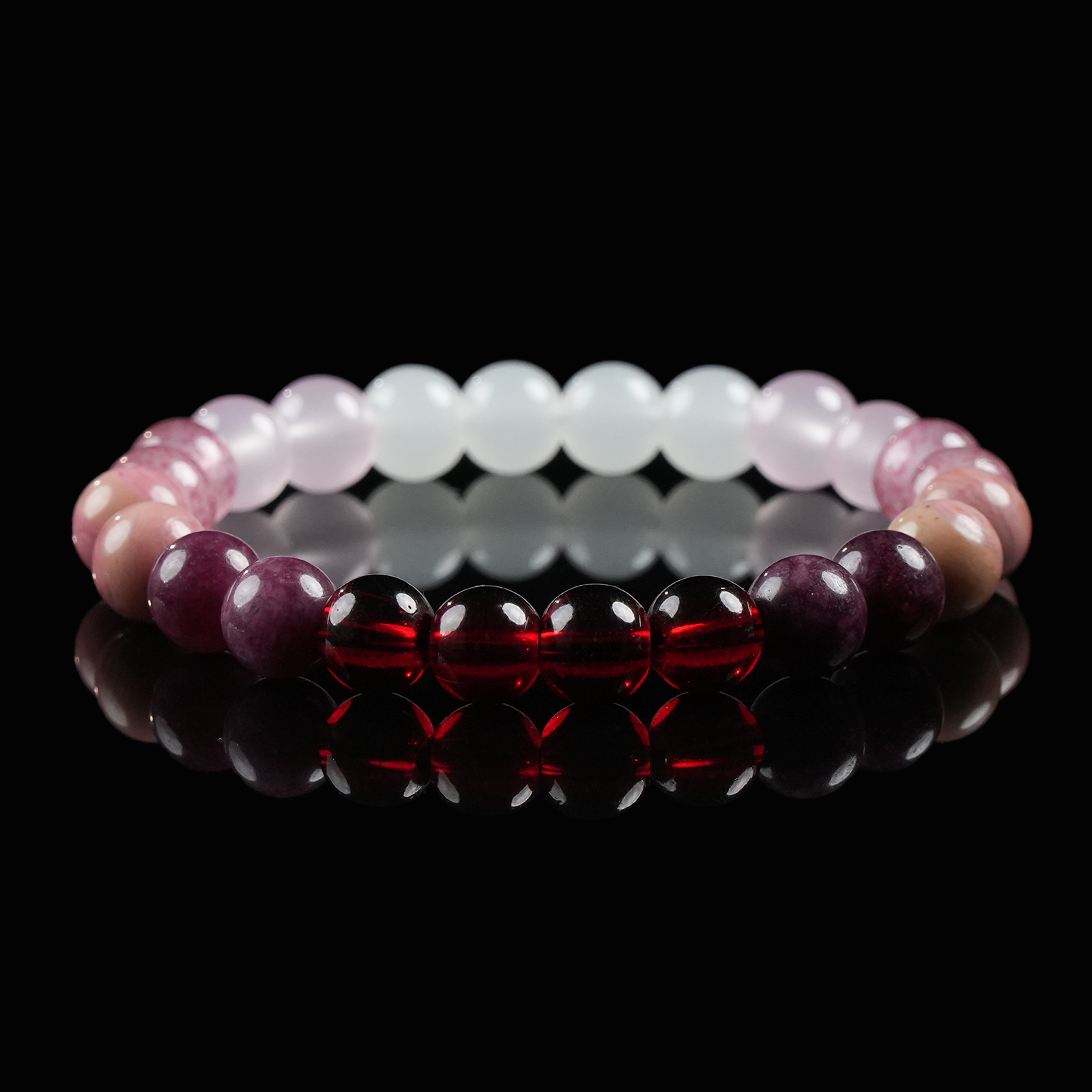 Close-up of a gemstone bracelet with vibrant red garnet, pink strawberry quartz, and soft rose quartz beads, symbolizing love, passion, and emotional wellness.
