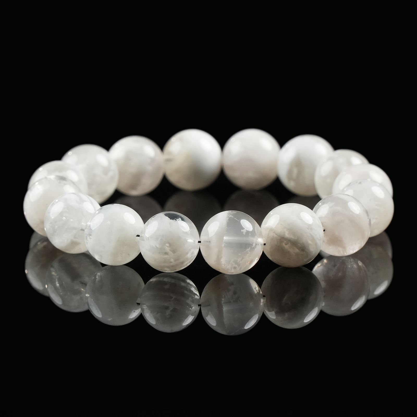 Snow phantom quartz bracelet made of polished white translucent crystal beads, shown on black reflective surface for clarity and light energy.