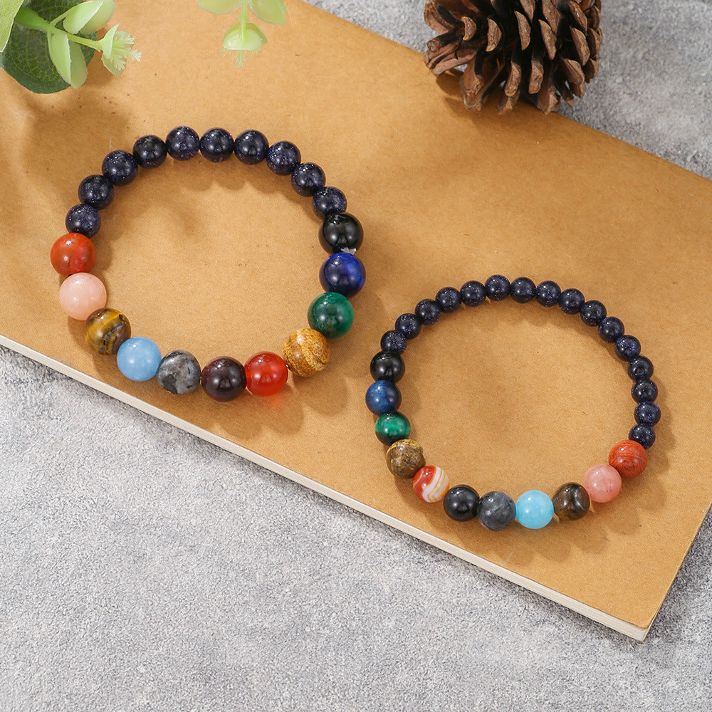 Two different-sized galaxy-themed bracelets featuring colorful planetary beads, presented on kraft paper background.