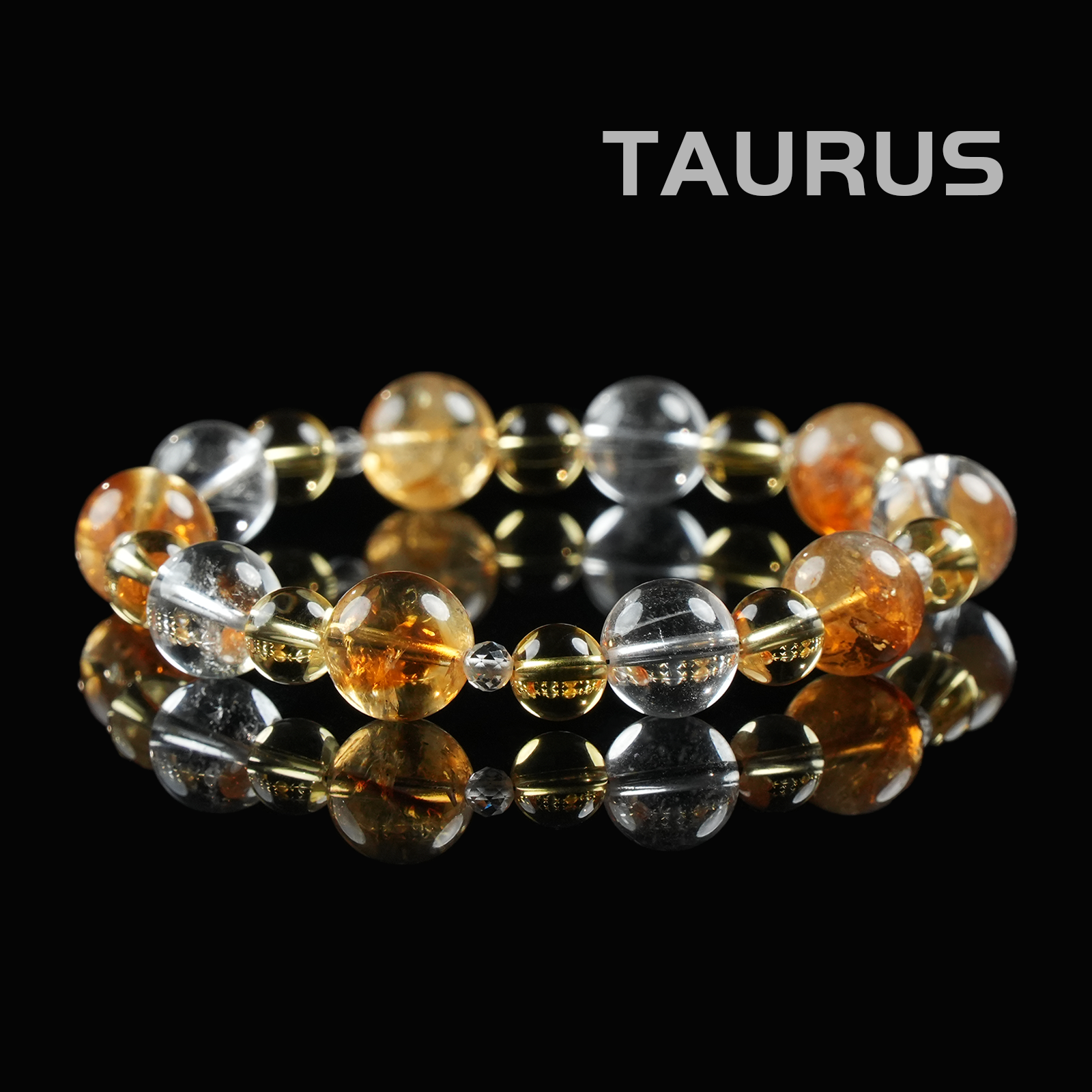 Flat lay of Taurus zodiac bracelet with golden citrine, clear quartz, and golden rutile crystal beads on black reflective background.