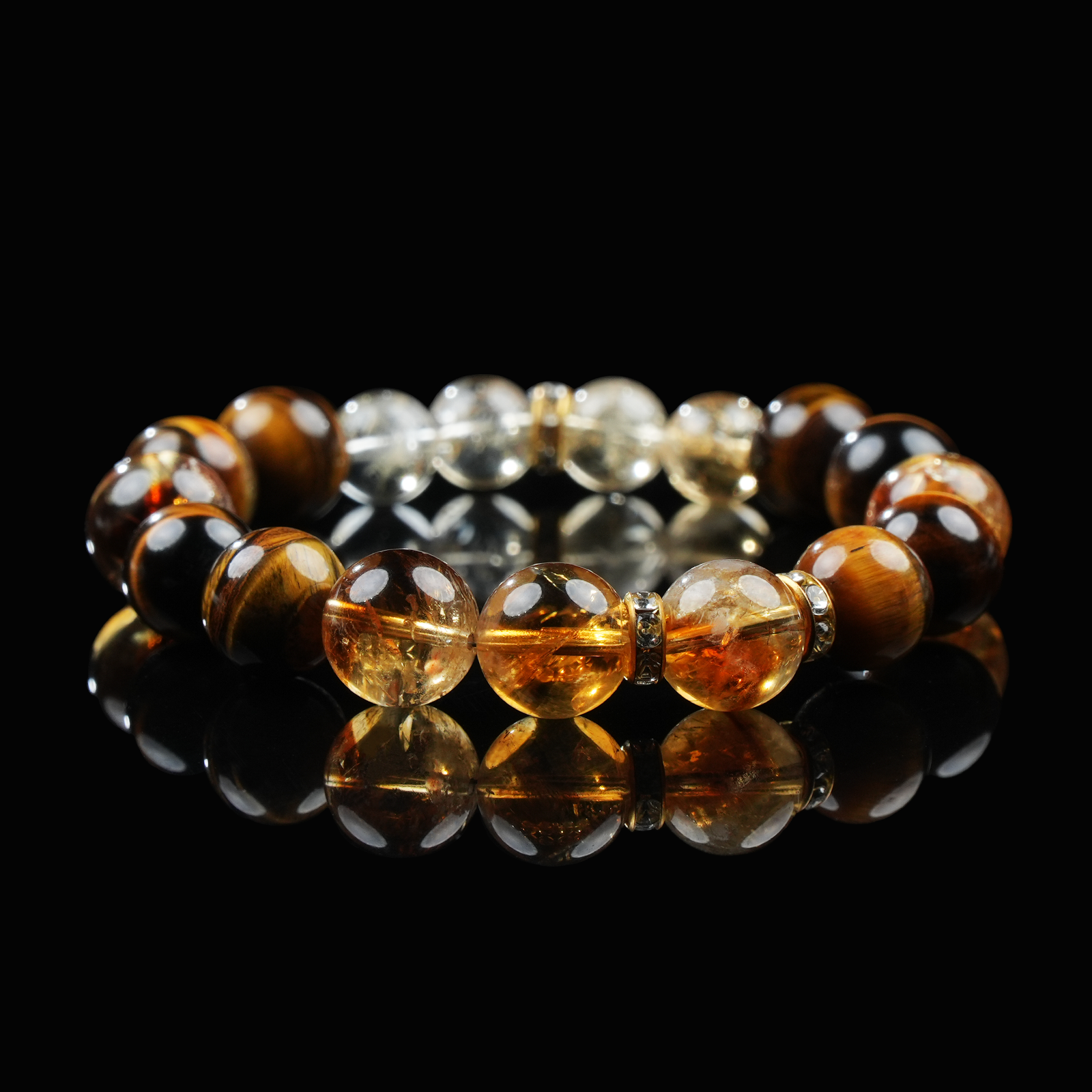A radiant beaded bracelet featuring golden-brown Tiger’s Eye, sparkling Citrine, and clear Quartz beads, arranged in a warm and luminous gradient, displayed on a glossy black reflective surface.