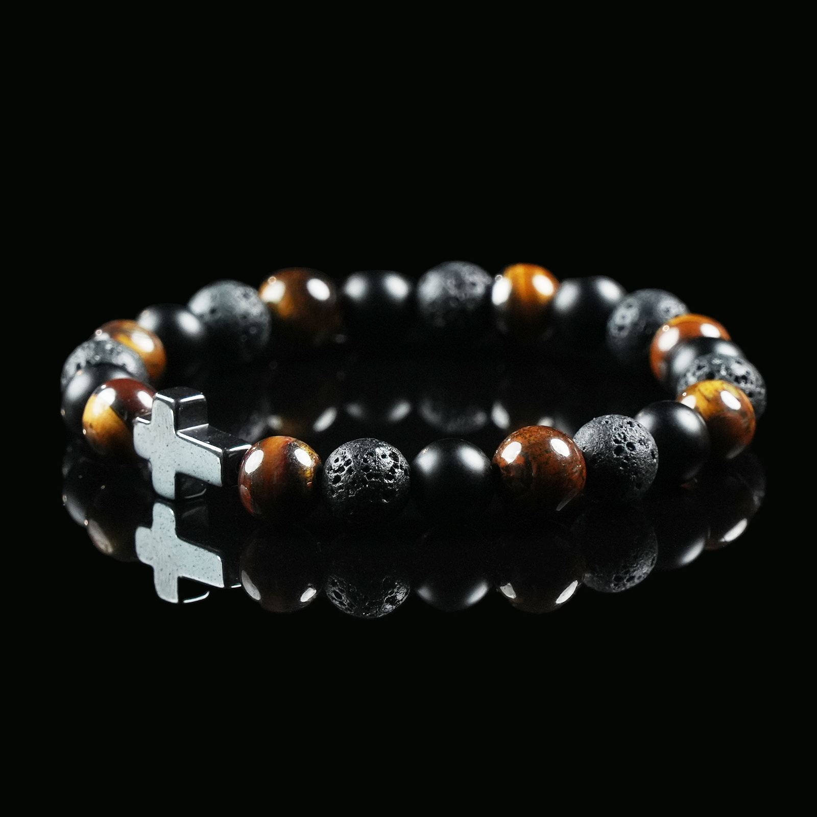 Bracelet made of tiger’s eye, lava stone, and obsidian beads with a silver cross charm, displayed on a black background to emphasize its earthy power and balance.