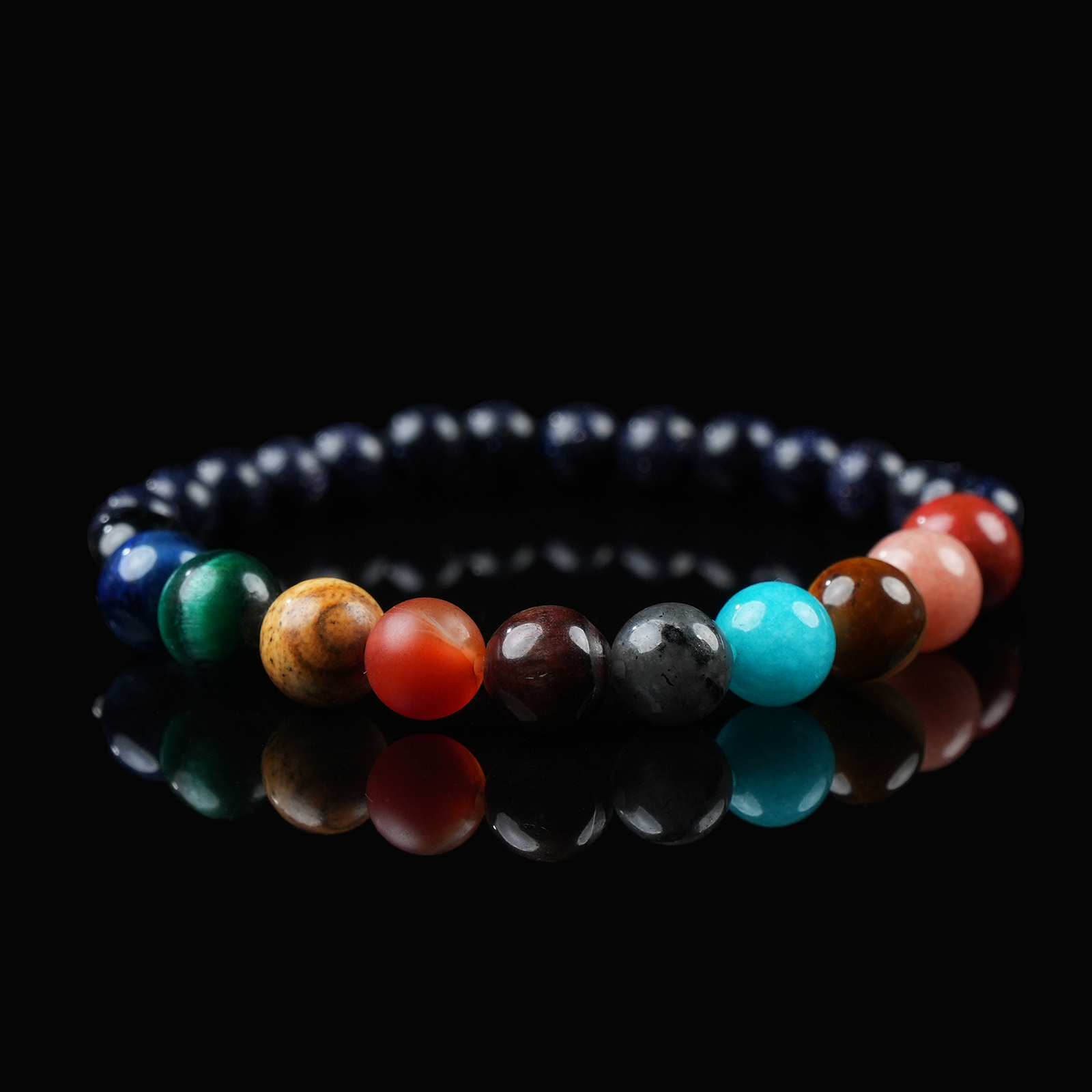 A close-up of a galaxy-inspired bracelet with multicolored crystal beads representing planets, set against a black reflective background.
