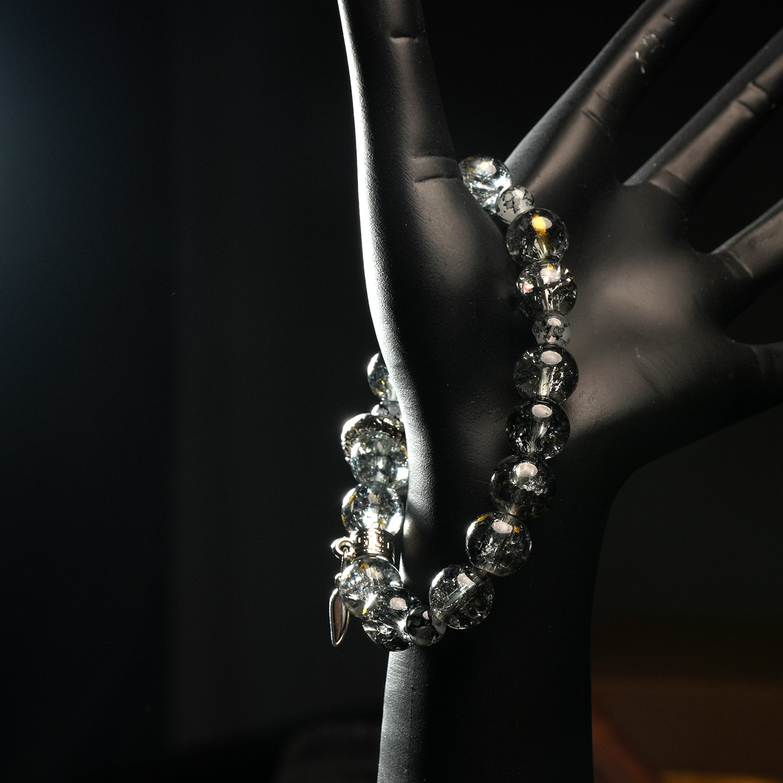 Celestial quartz bracelet on mannequin hand, featuring dark glass beads and detailed charms, representing protection and alignment.