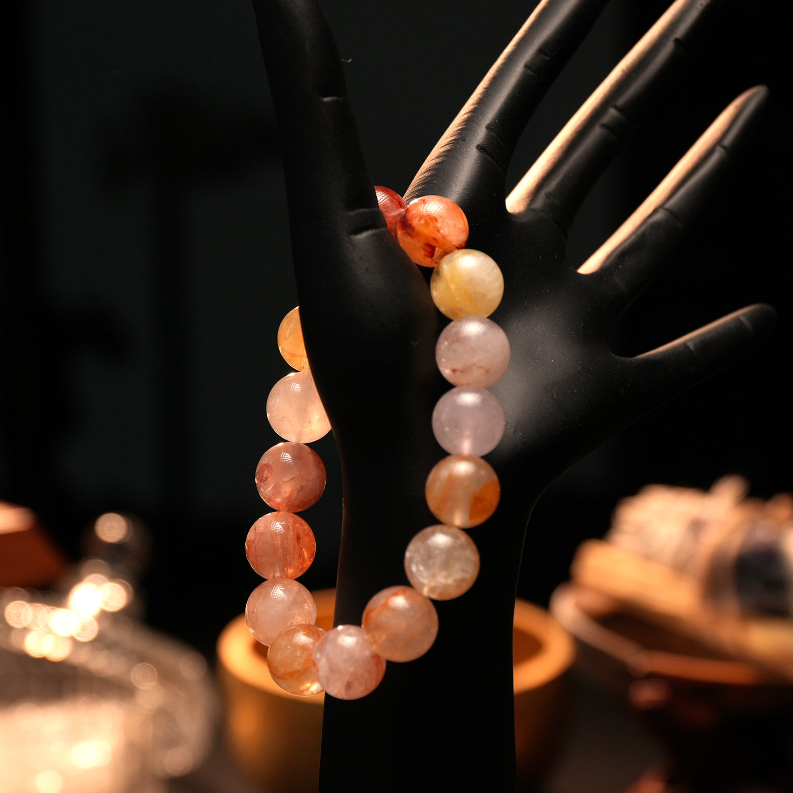 Bracelet styled on a black mannequin hand, lit with warm glow to enhance the vibrant red and amber hues, conveying balance and vitality.