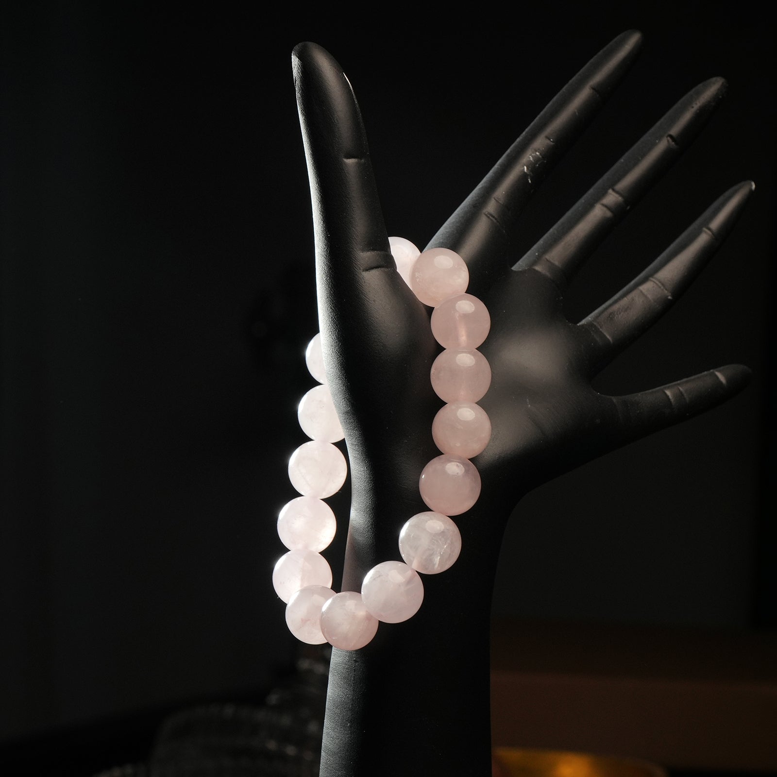 Rose quartz bracelet worn on mannequin hand, showcasing soft pink tone beads for heart chakra and gentle emotional support.