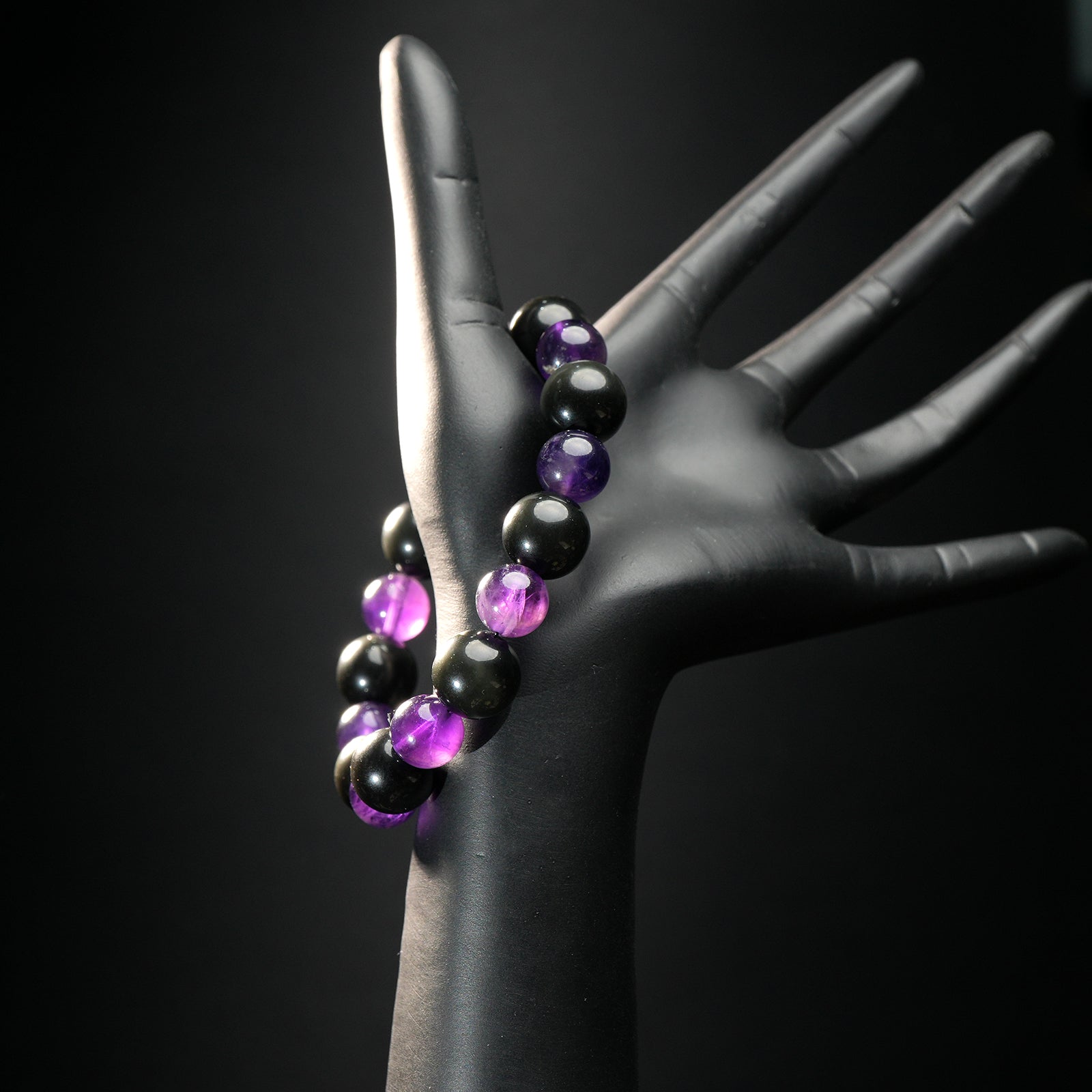 Scorpio astrology bracelet shown on a black mannequin hand, with glossy amethyst and grounding hematite beads for intuition and power.