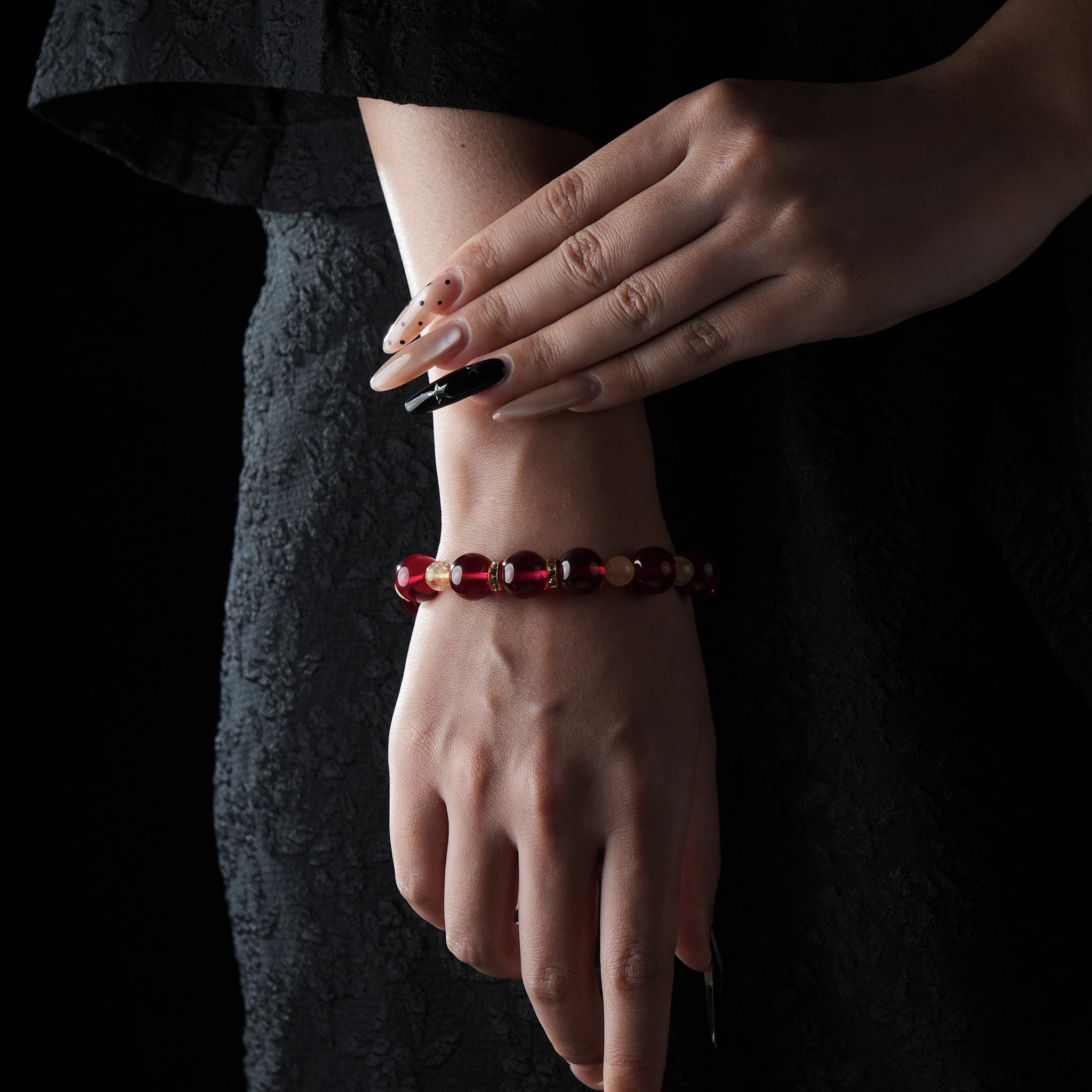A model wearing the garnet and golden quartz beaded bracelet on the wrist, paired with a dark outfit, emphasizing the bracelet's radiant, luxurious tones.