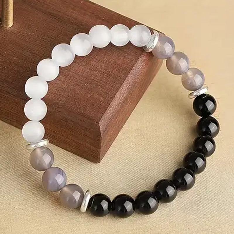 Bracelet laid on a wooden surface with alternating white, gray, and black beads, representing duality, grounding energy, and inner clarity.