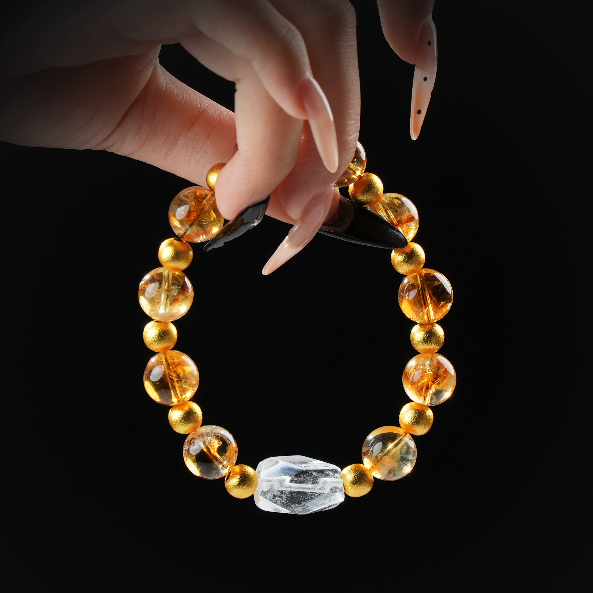 Citrine and clear quartz beaded bracelet with matte gold spacers and raw quartz centerpiece, held by hand on black background for prosperity and energy.